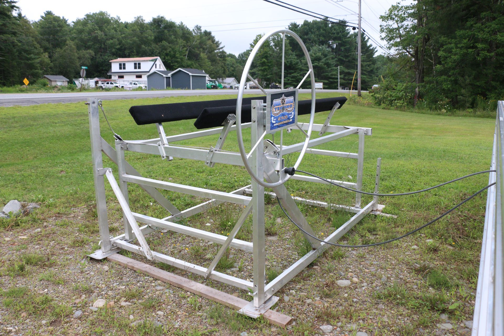 A boat lift is sitting in the middle of a grassy field.