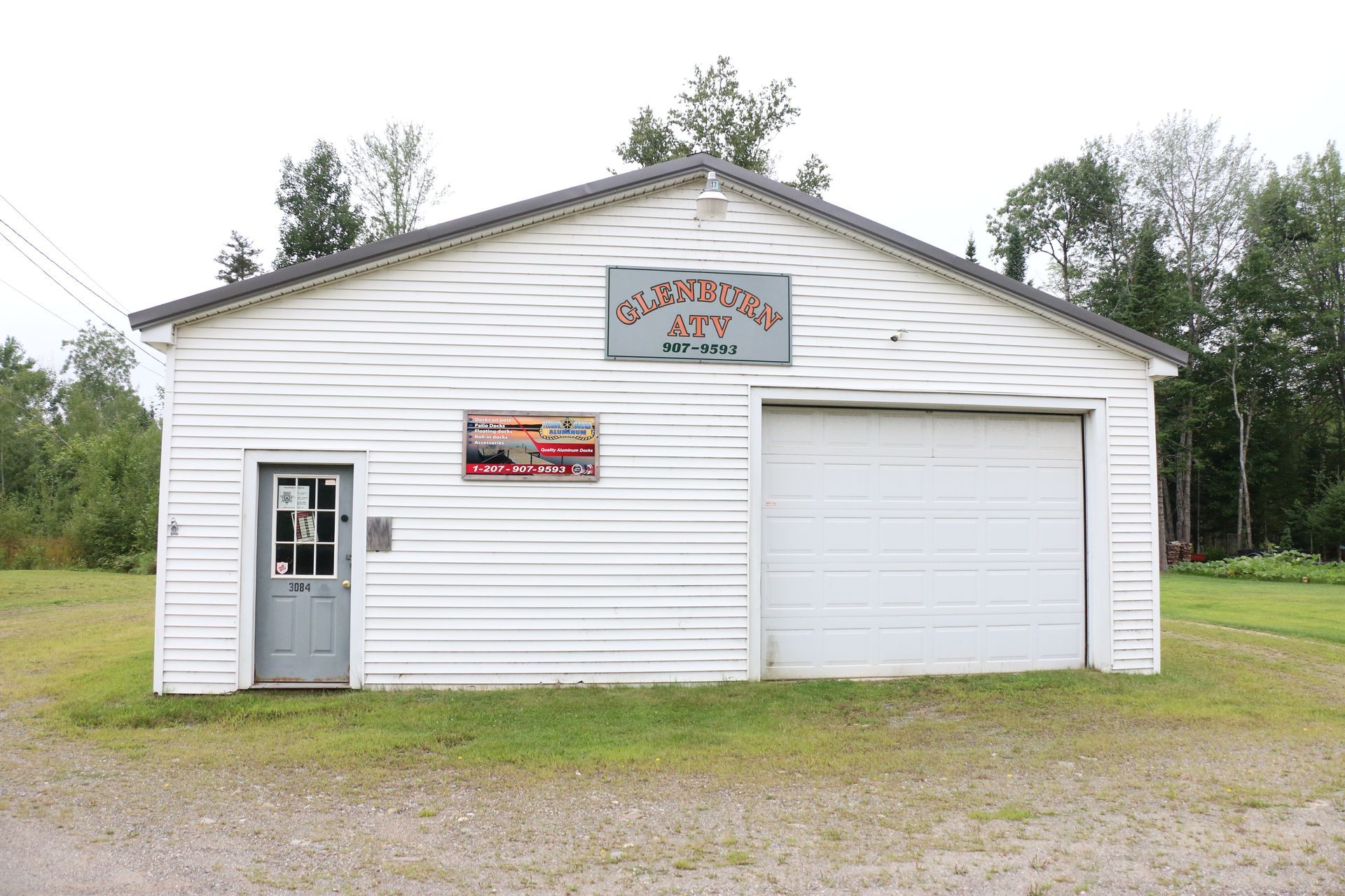 A white building with a garage door and a sign that says ' ambulance ' on it
