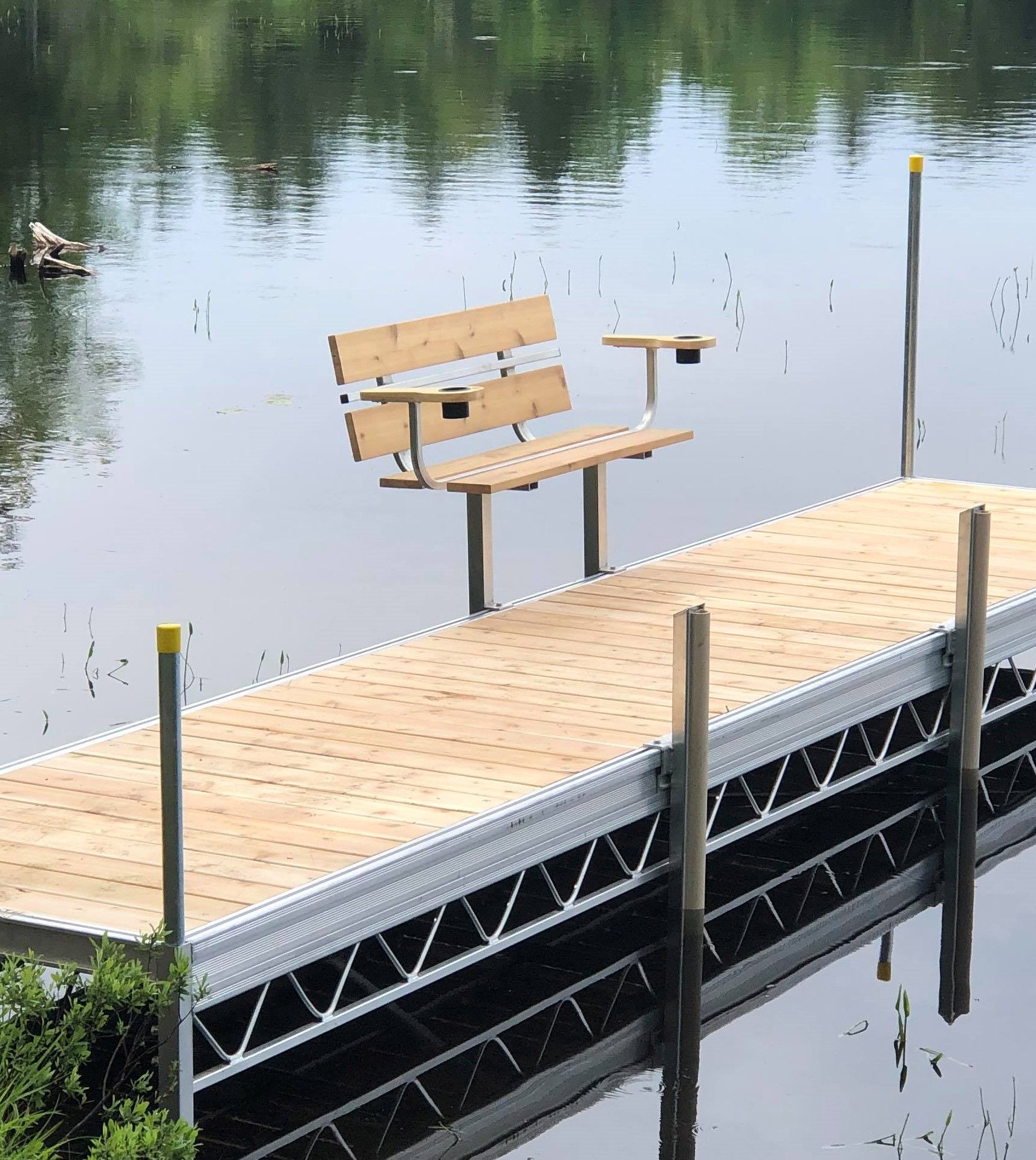 A wooden bench sits on a dock overlooking a lake