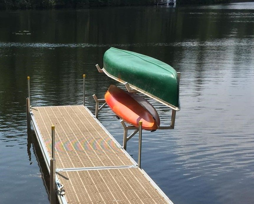 A dock with two canoes and two kayaks on it