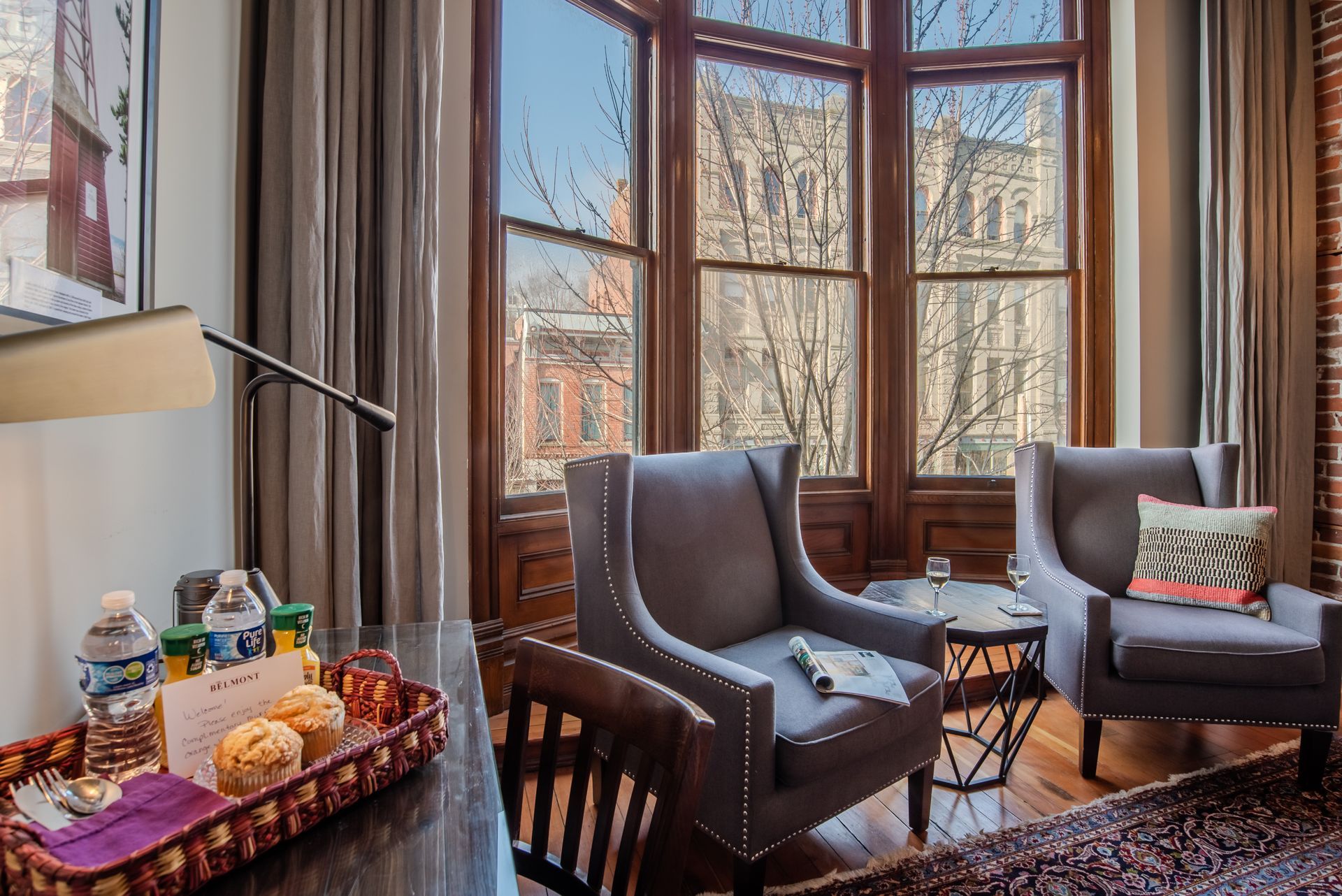 A hotel room with two chairs and a table with a tray of food on it.