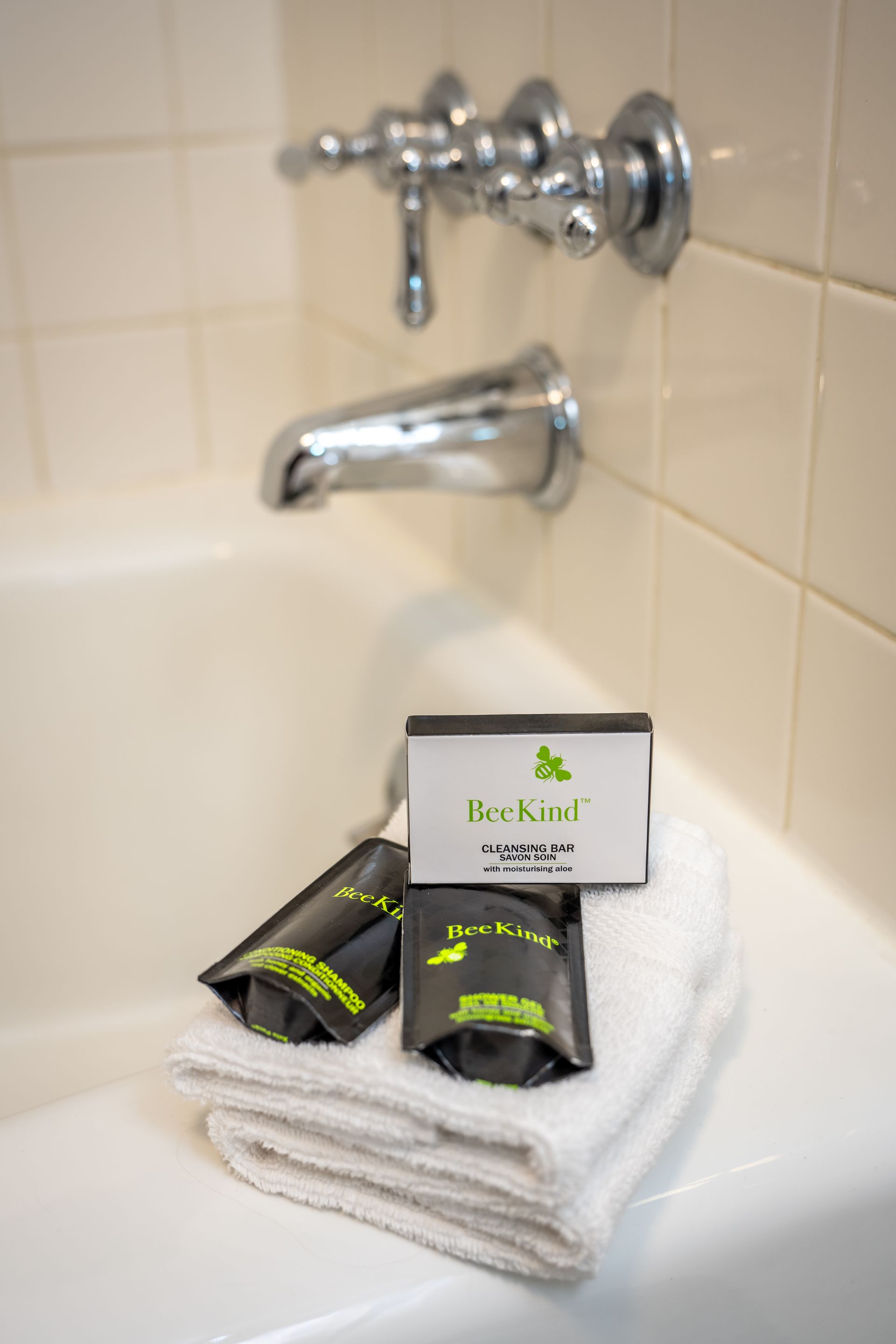 A stack of towels sits on a bathtub next to a bar of bergamot soap