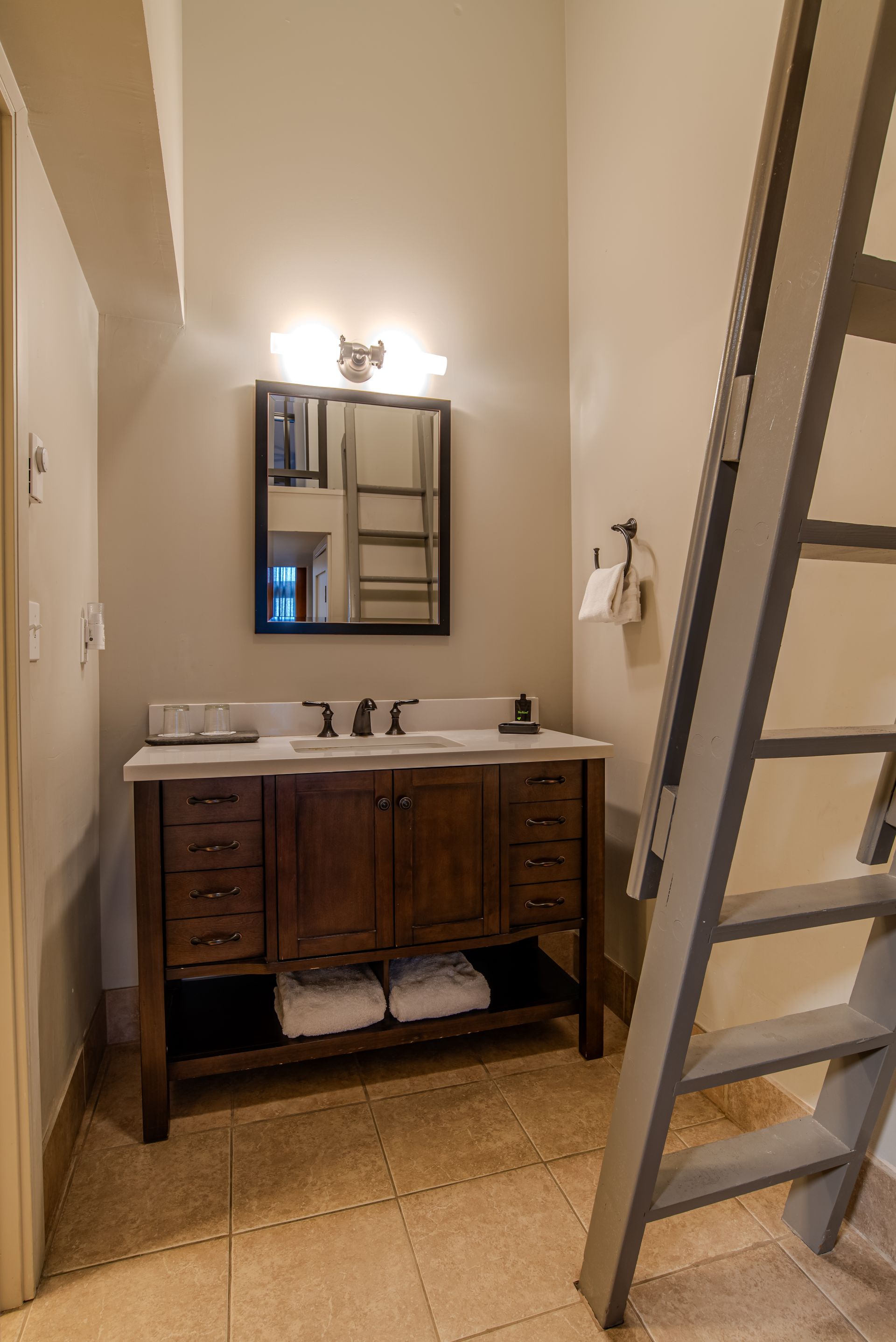 A bathroom with two sinks , a mirror and a ladder.