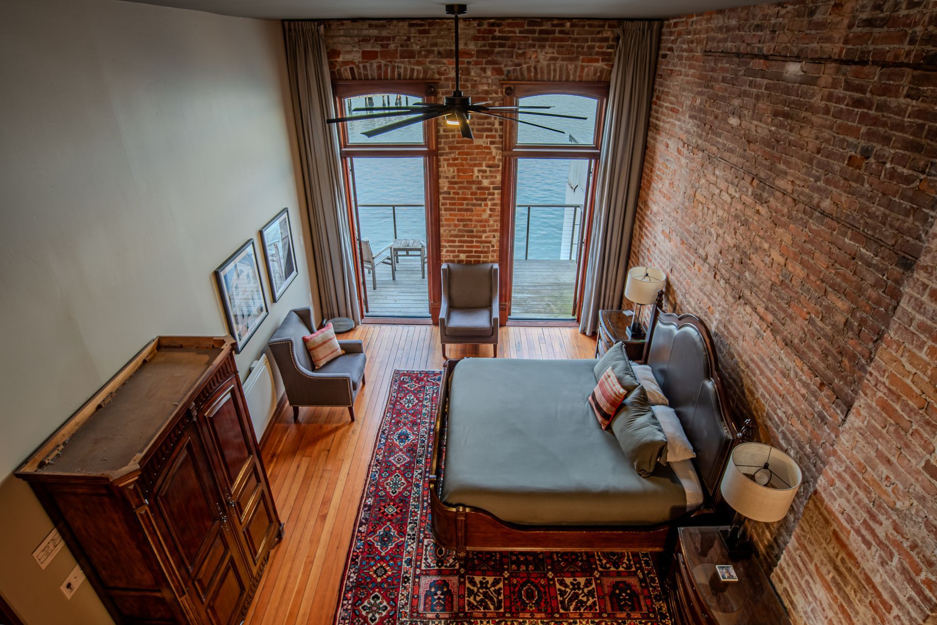An aerial view of a bedroom with a bed , chairs , and a ceiling fan.