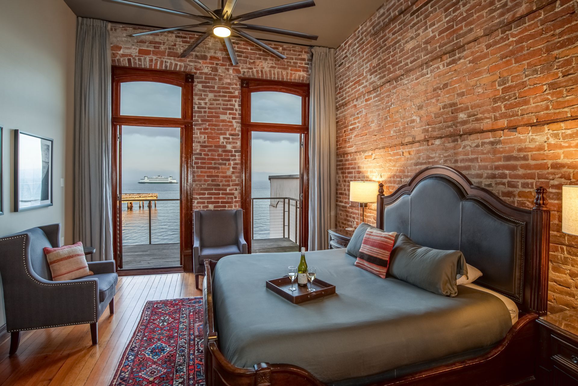 A bedroom with a king size bed , chairs , and a ceiling fan.