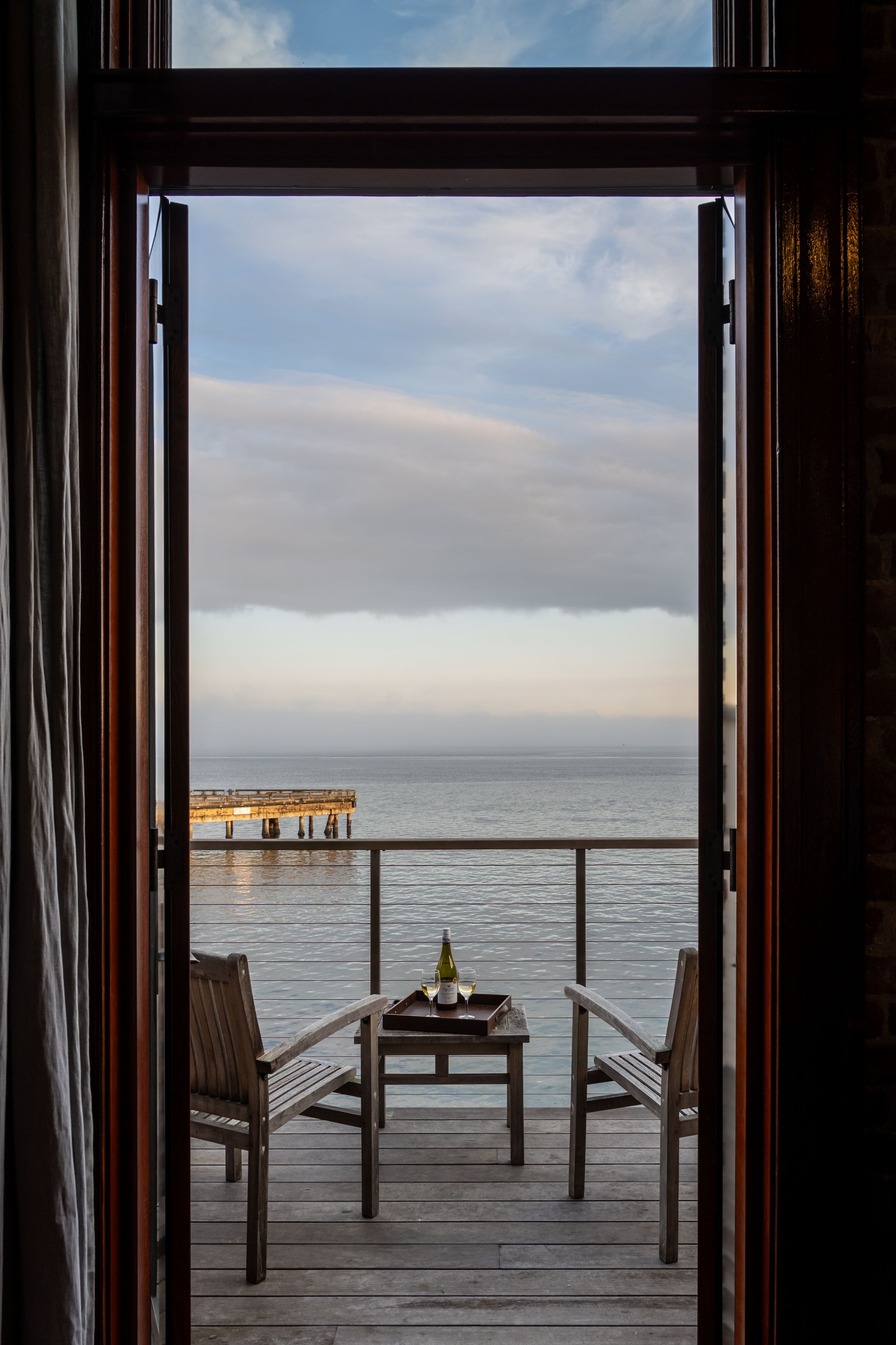 A balcony with chairs and a table overlooking the ocean.