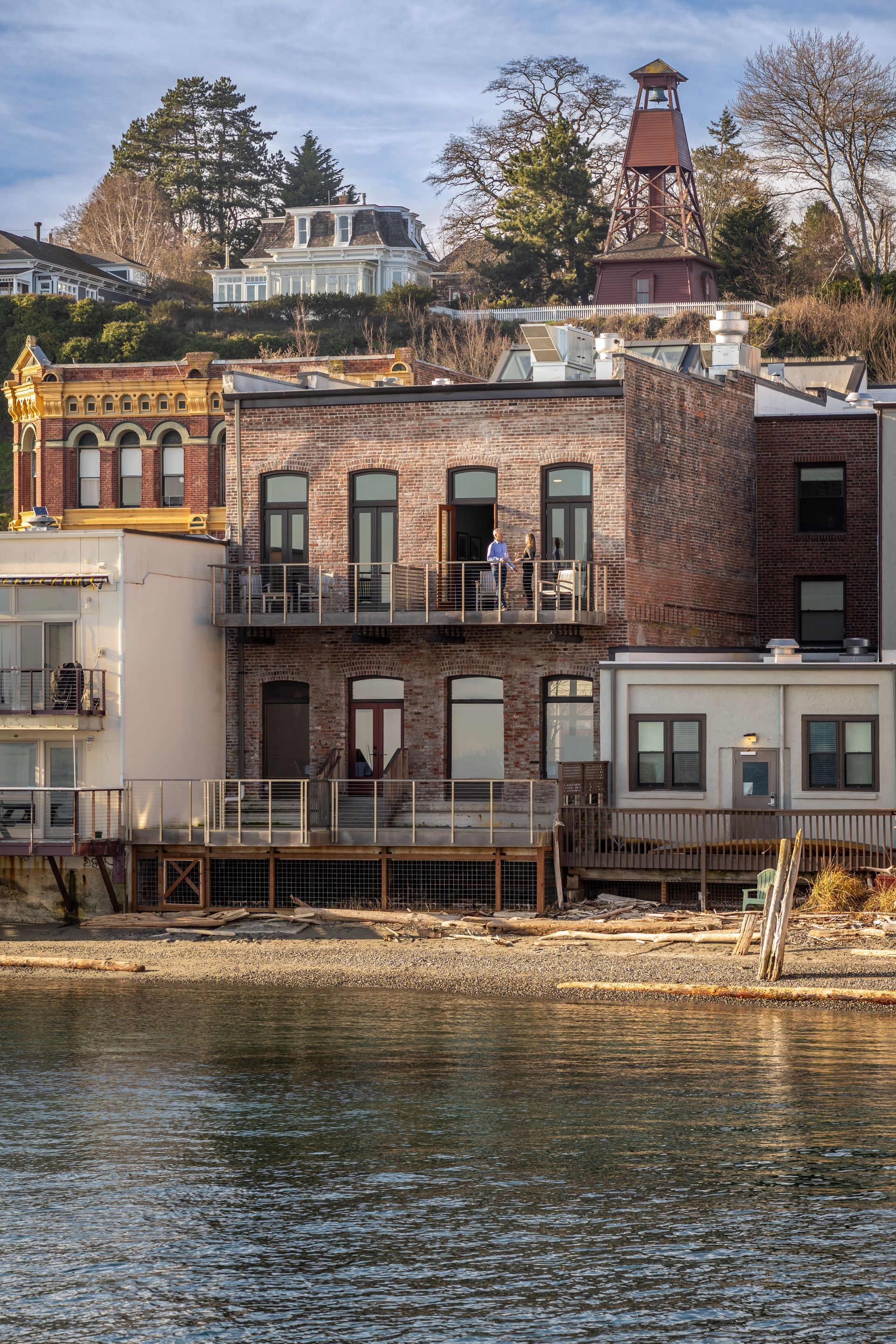 A brick building with a balcony overlooking a body of water