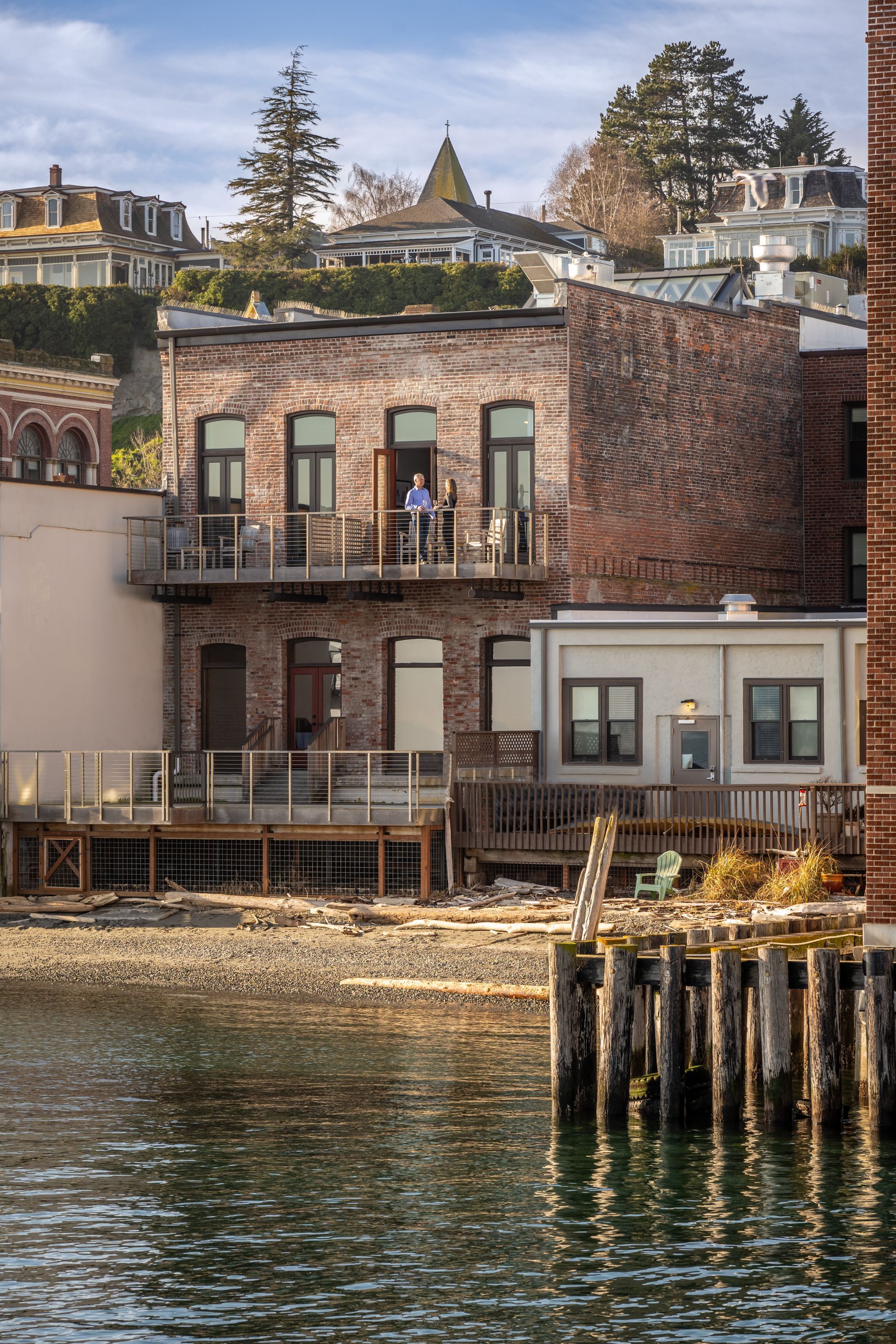 A brick building with a balcony overlooking a body of water.