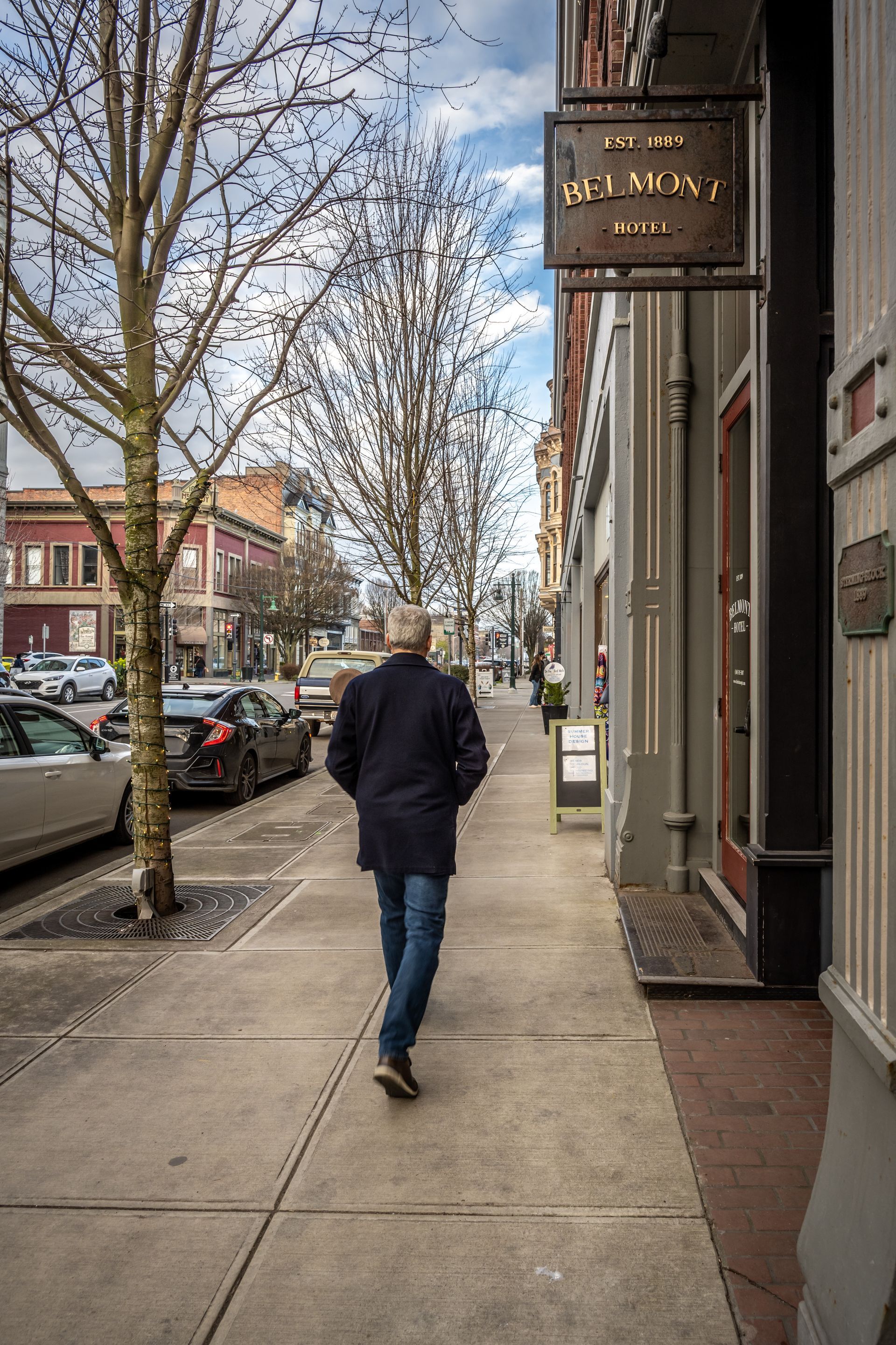A man is walking down a sidewalk in front of a building.