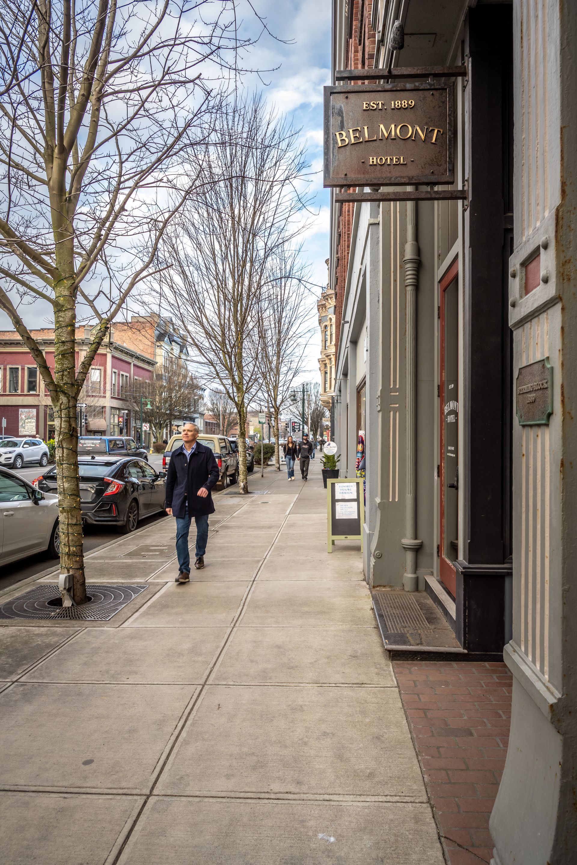 A man is walking down a sidewalk in front of a building.