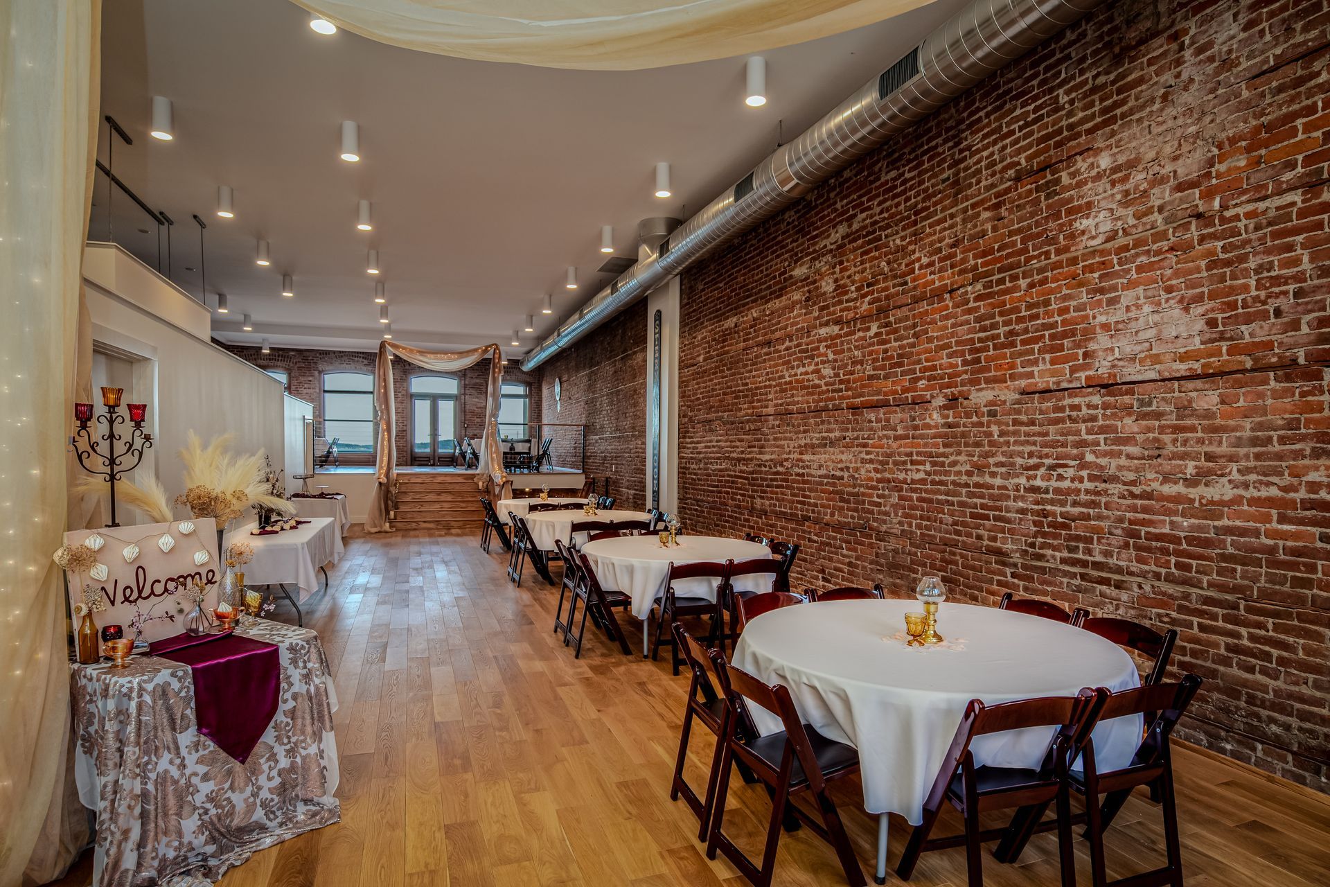 A large room with tables and chairs in front of a brick wall.