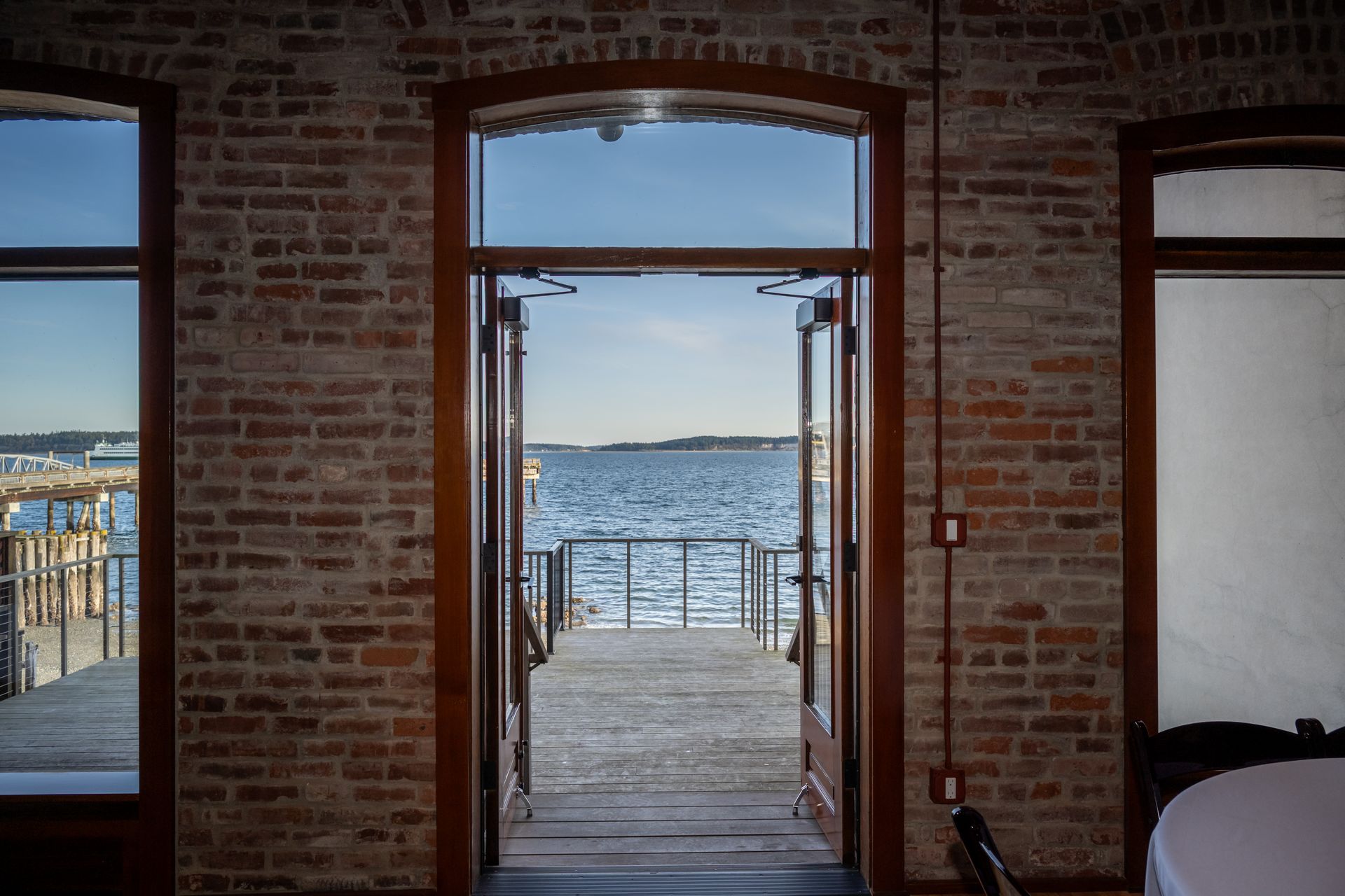 A room with a table and chairs and a view of the water through a doorway.