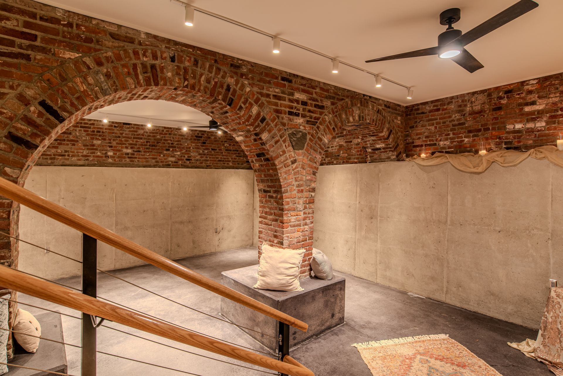 There is a ceiling fan in the room with a brick wall.