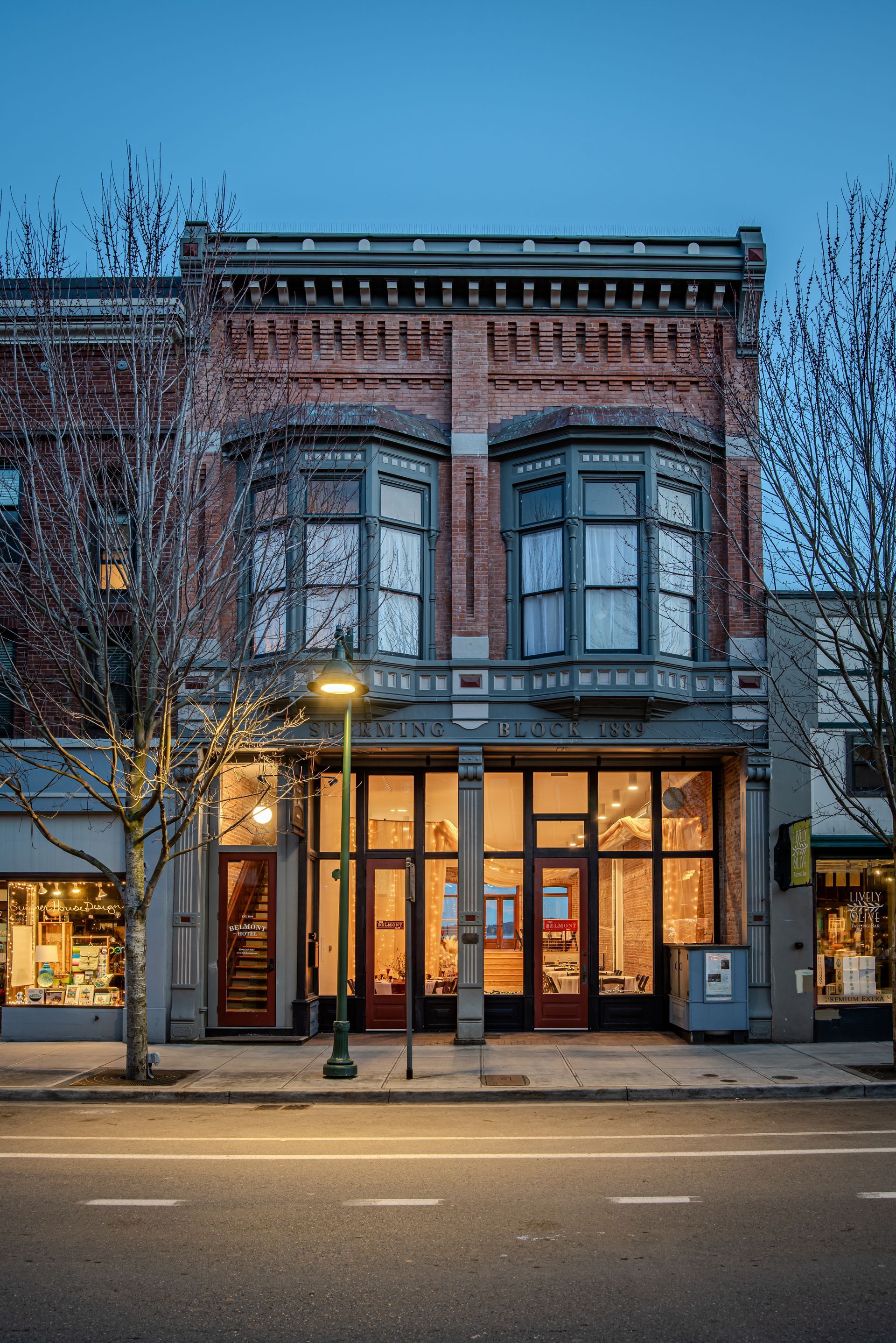 A large brick building with a lot of windows is on the corner of a city street.