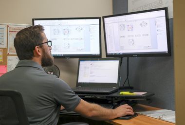 Male worker with glasses working on computer with two extra monitors