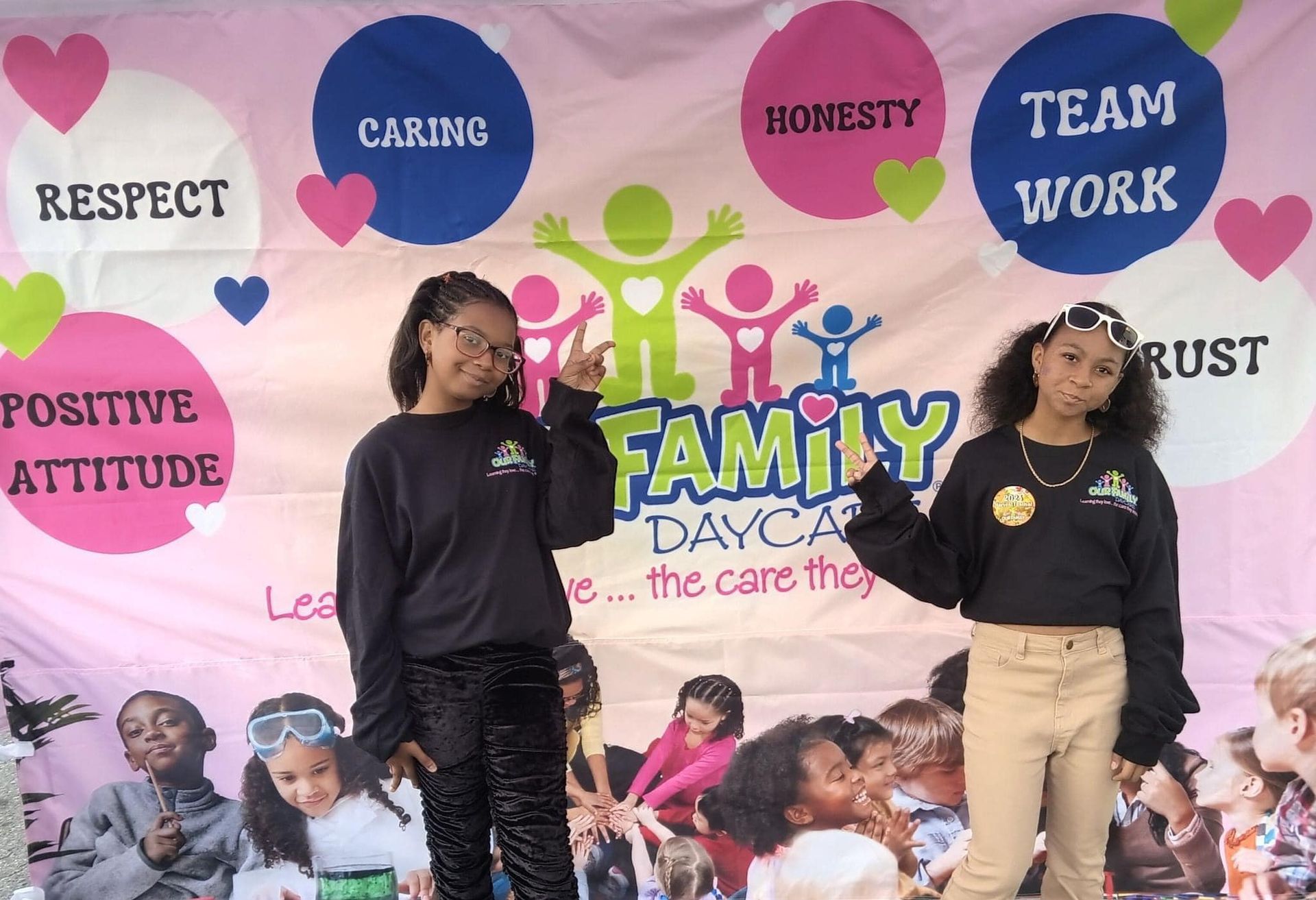 Two girls standing in front of a family daycare banner