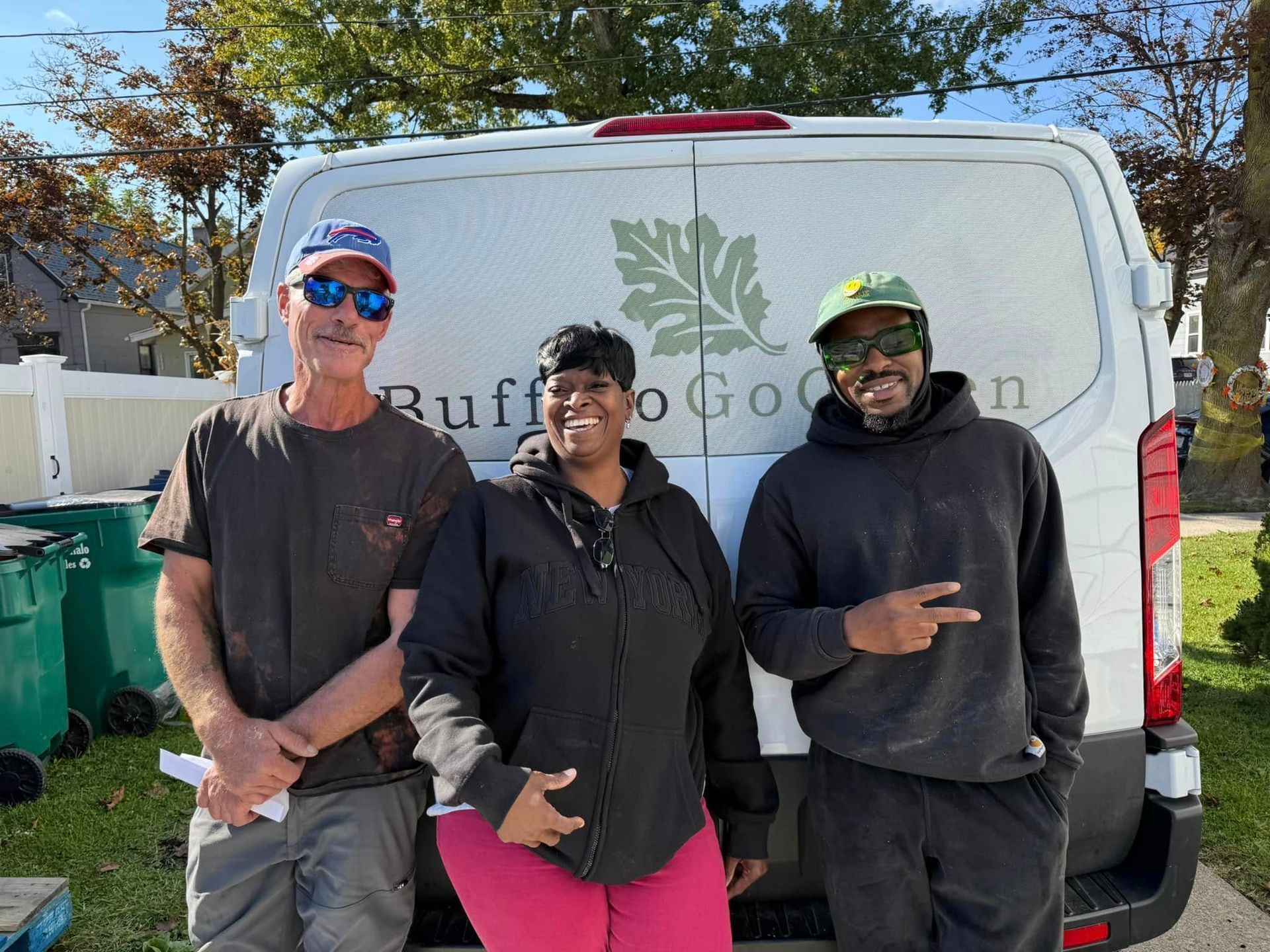 Three people are standing in front of a white van.