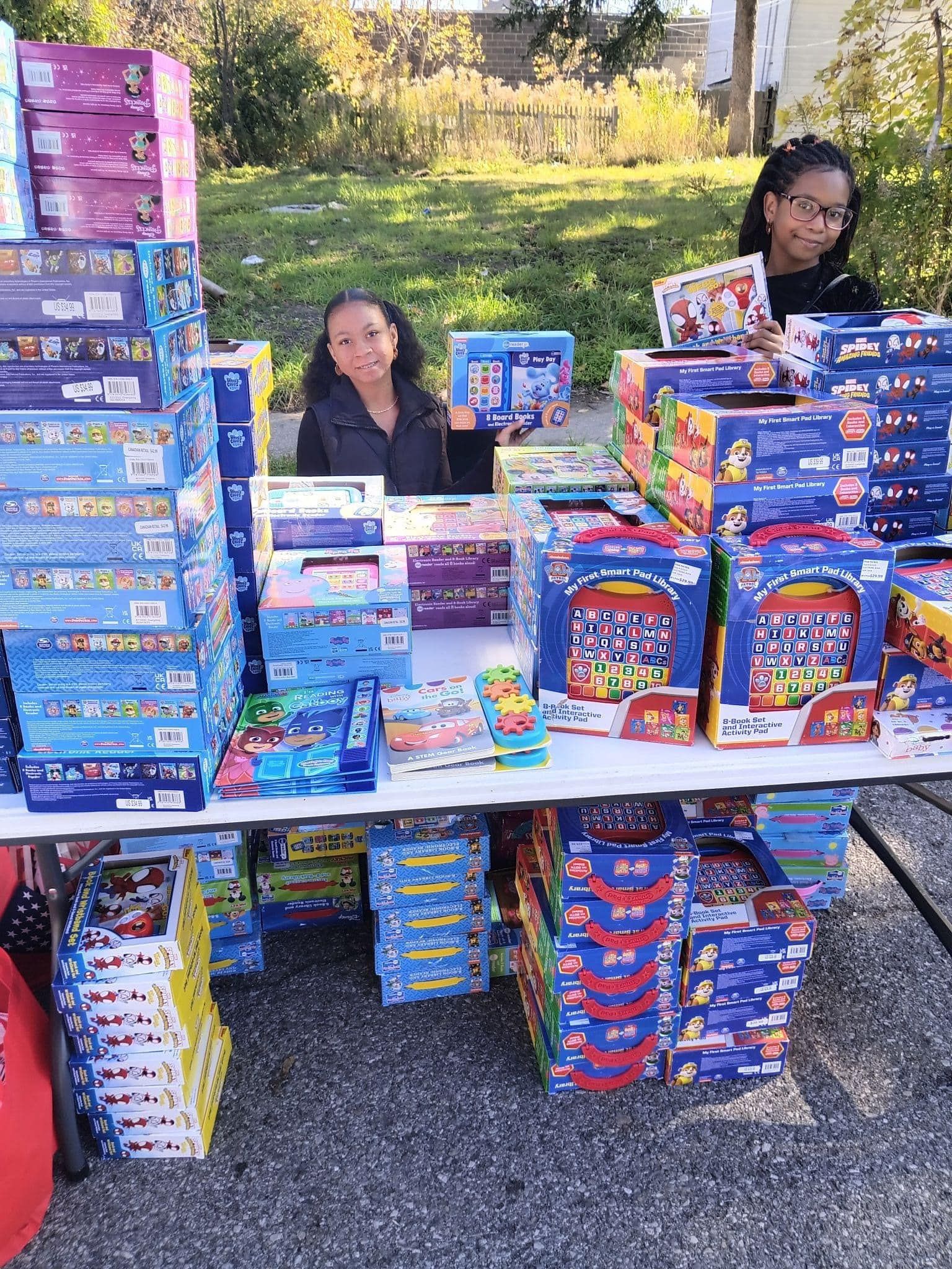 Two girls are sitting at a table filled with lots of toys.