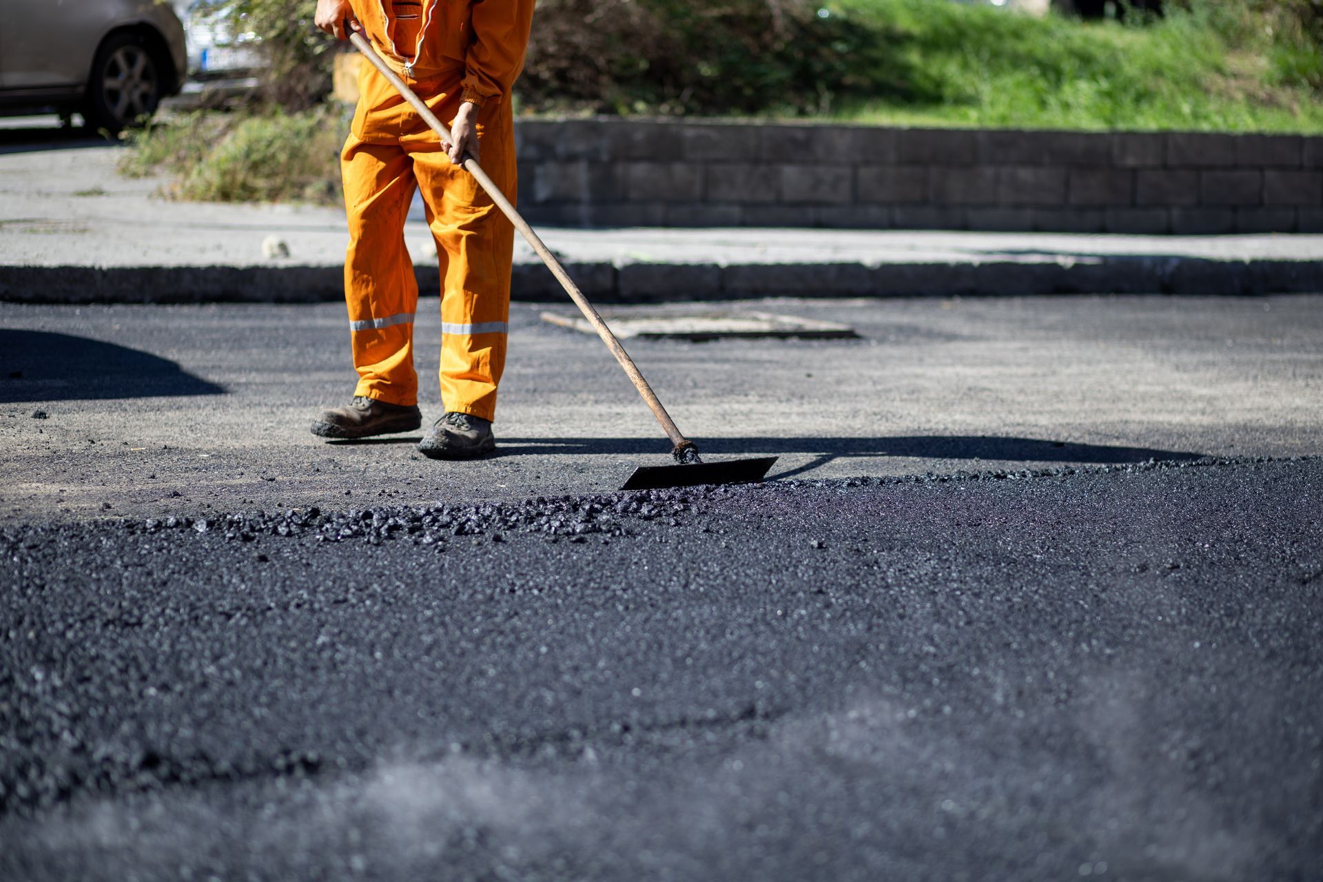 A worker applying sealant to an asphalt driveway, demonstrating expert driveway paving services.
