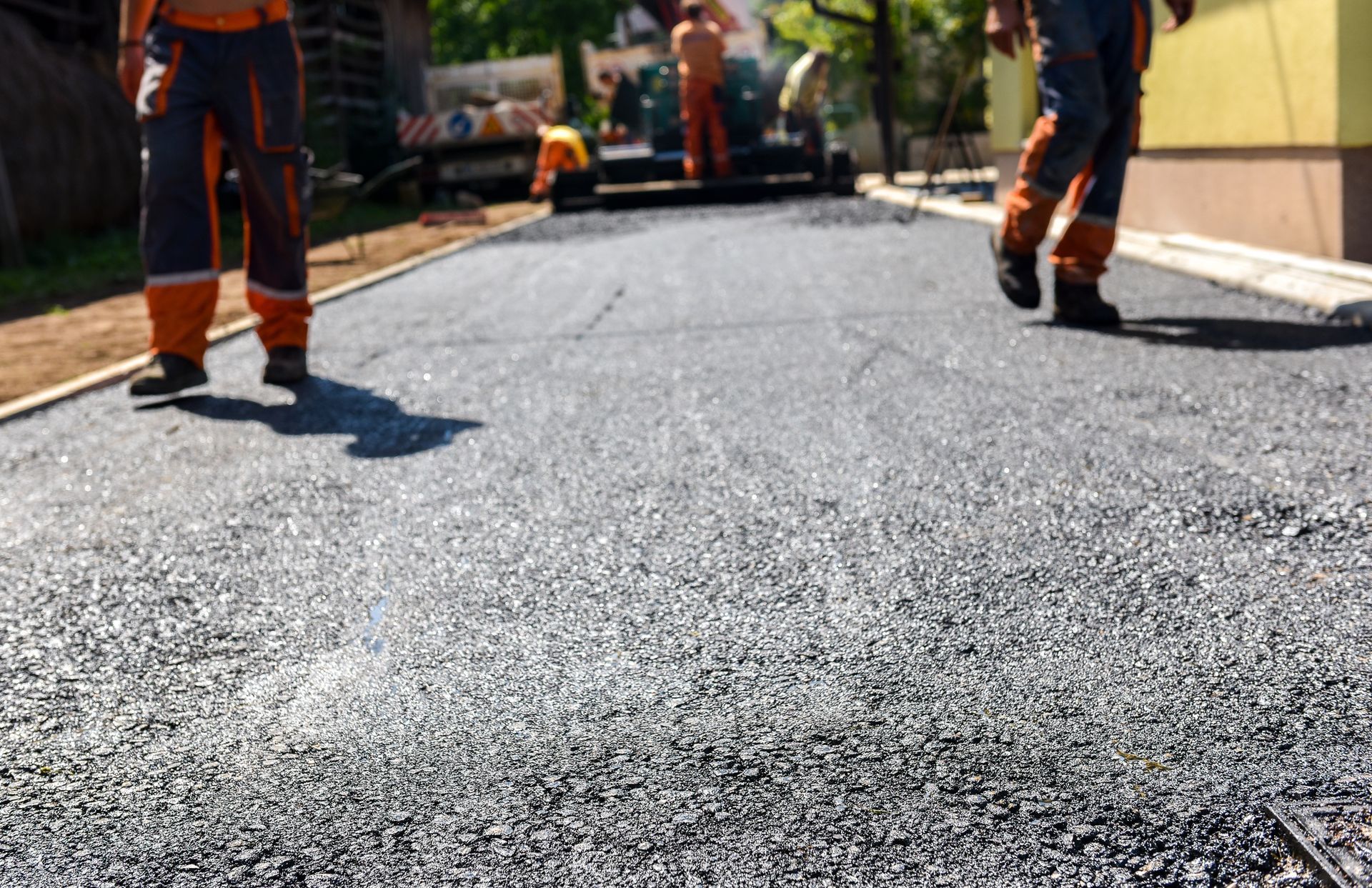 Workers paving a smooth asphalt driveway, showcasing professional driveway paving services.