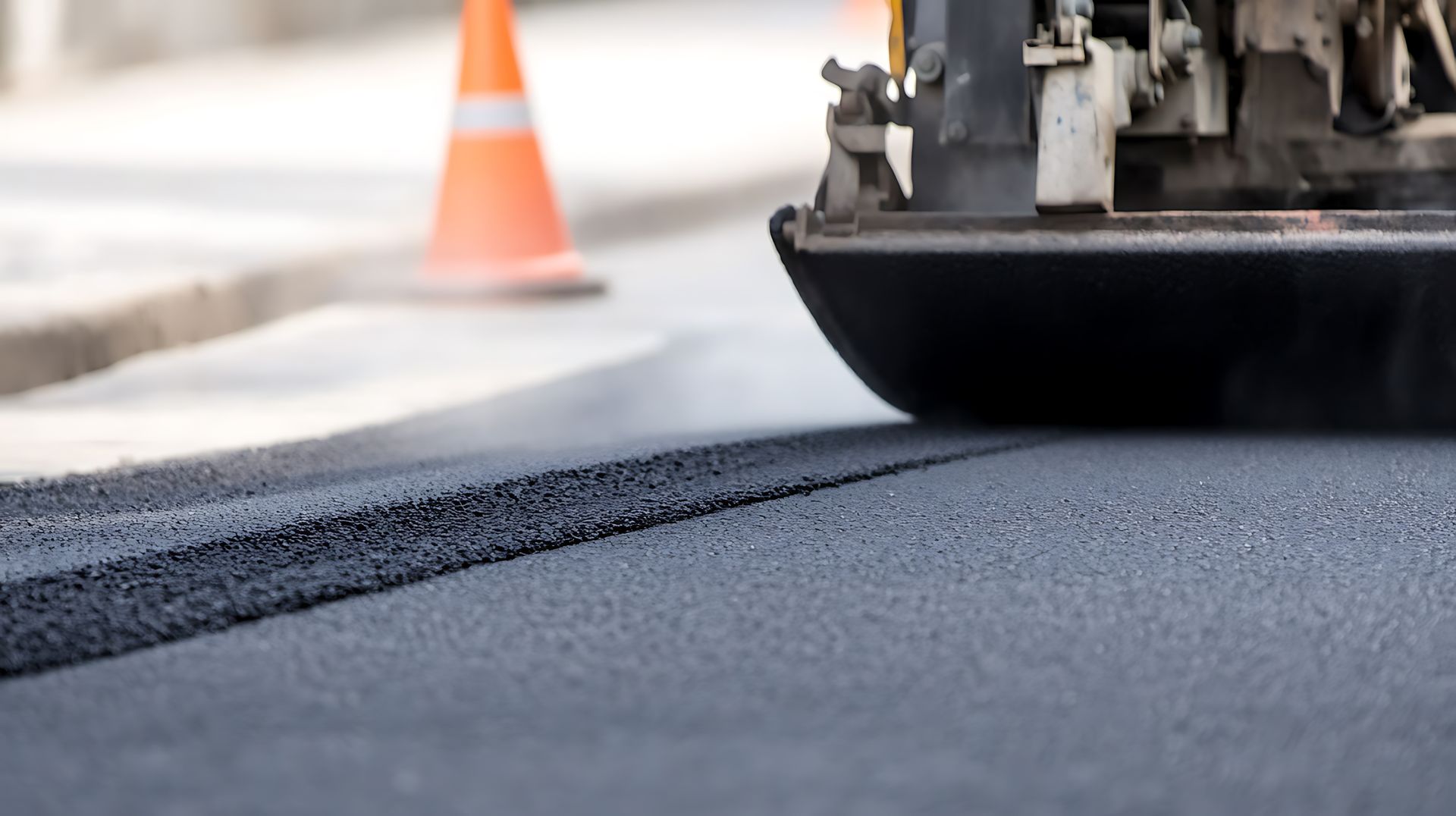 An asphalt paver machine in the process of laying a fresh layer of asphalt for road construction.