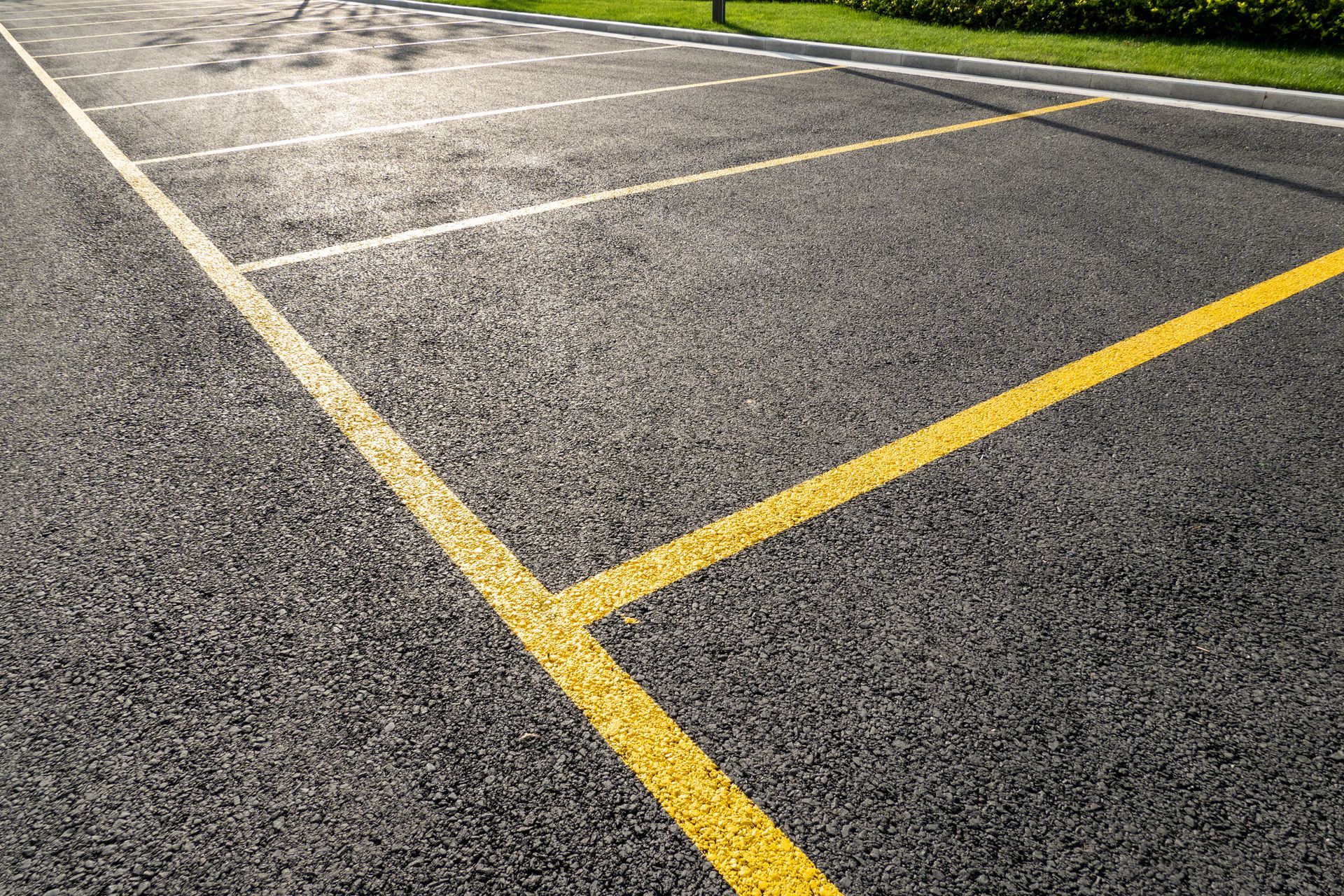Asphalt surface with yellow and white painted lines for parking or a play area.