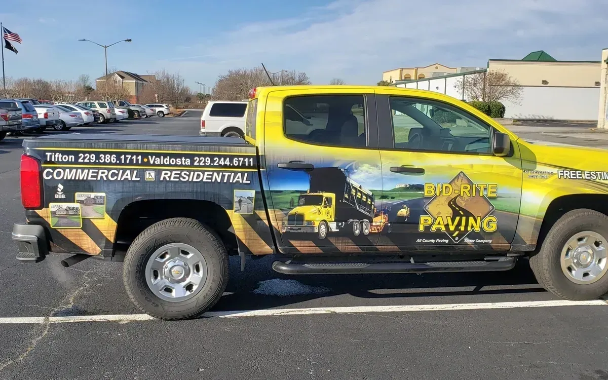 Yellow Big Rite Paving truck parked in a parking lot. Advertisement on the side.
