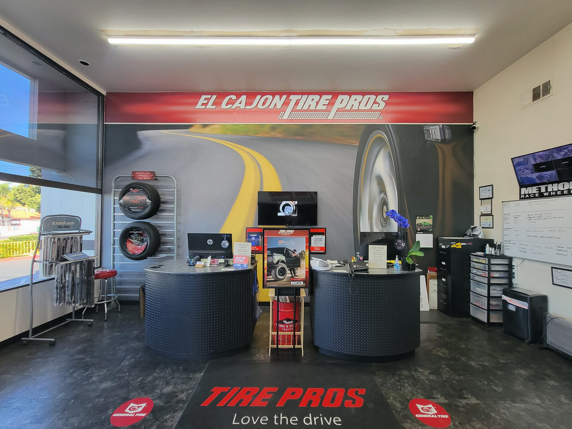 Interior of an El Cajon Tire Pros store with two service counters, branding, and a road-themed wall graphic. | El Cajon Tire Pros