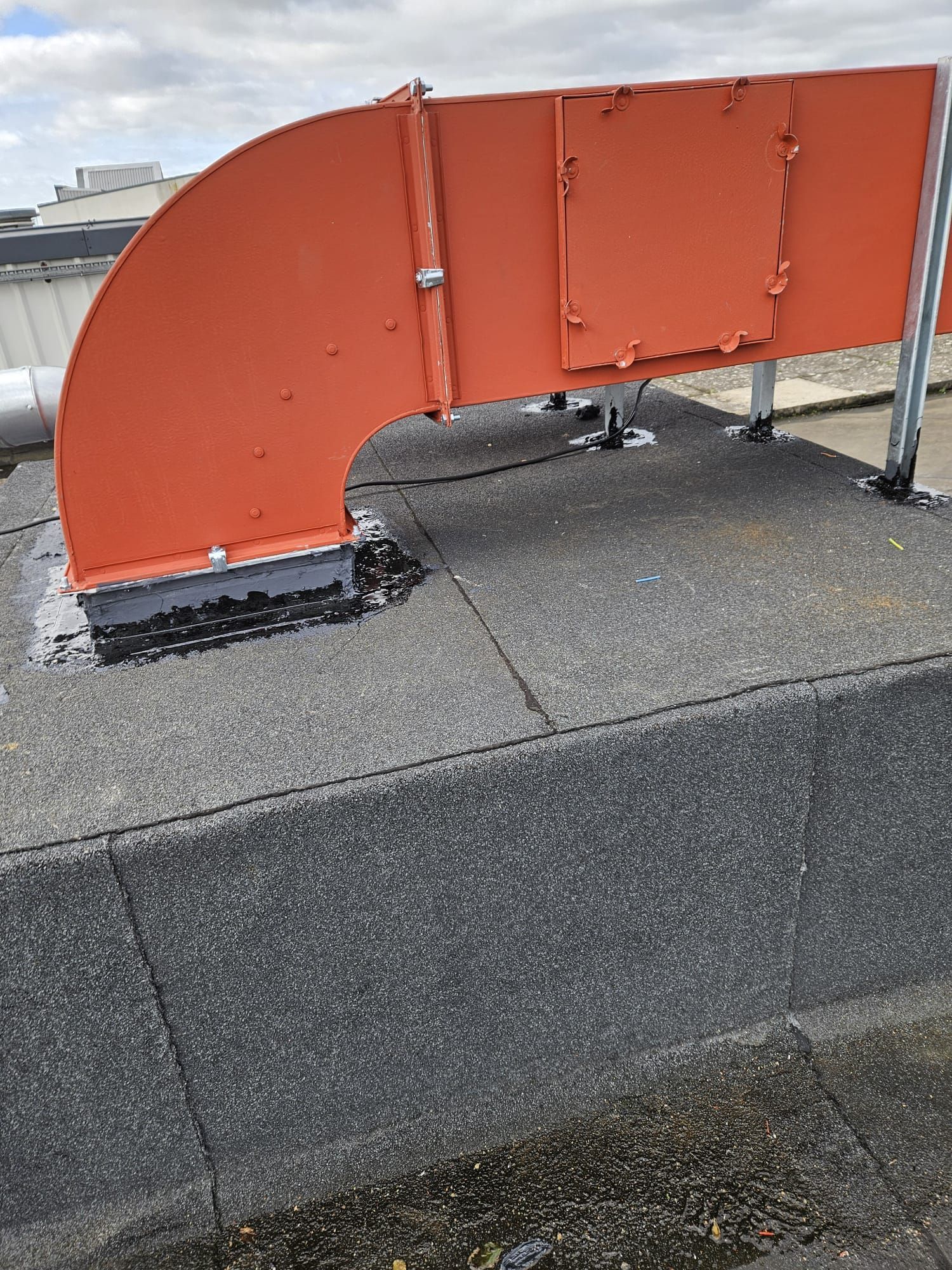 Orange HVAC ductwork on a flat roof, sealed with dark sealant.