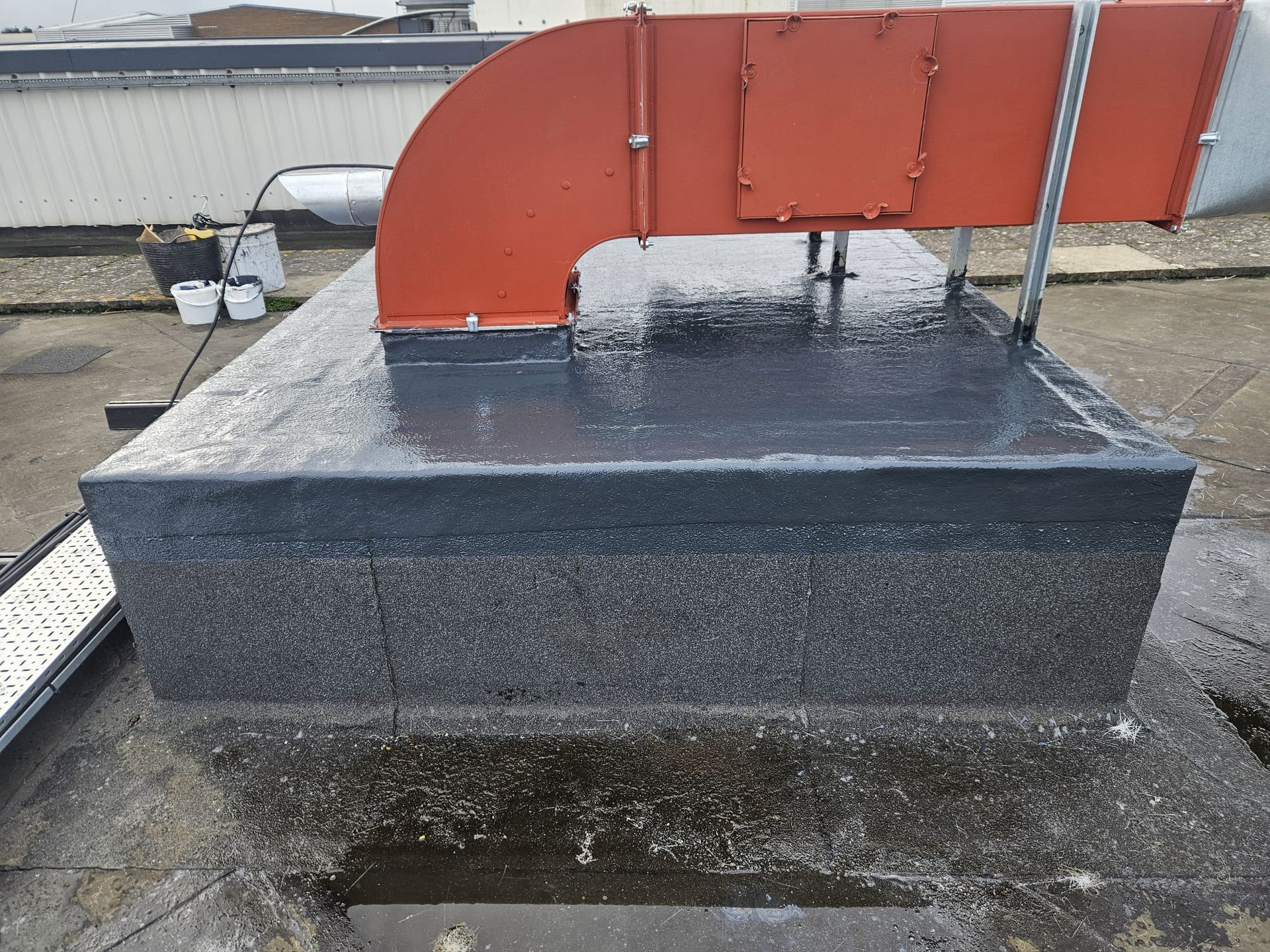 Black rooftop structure with red ductwork.