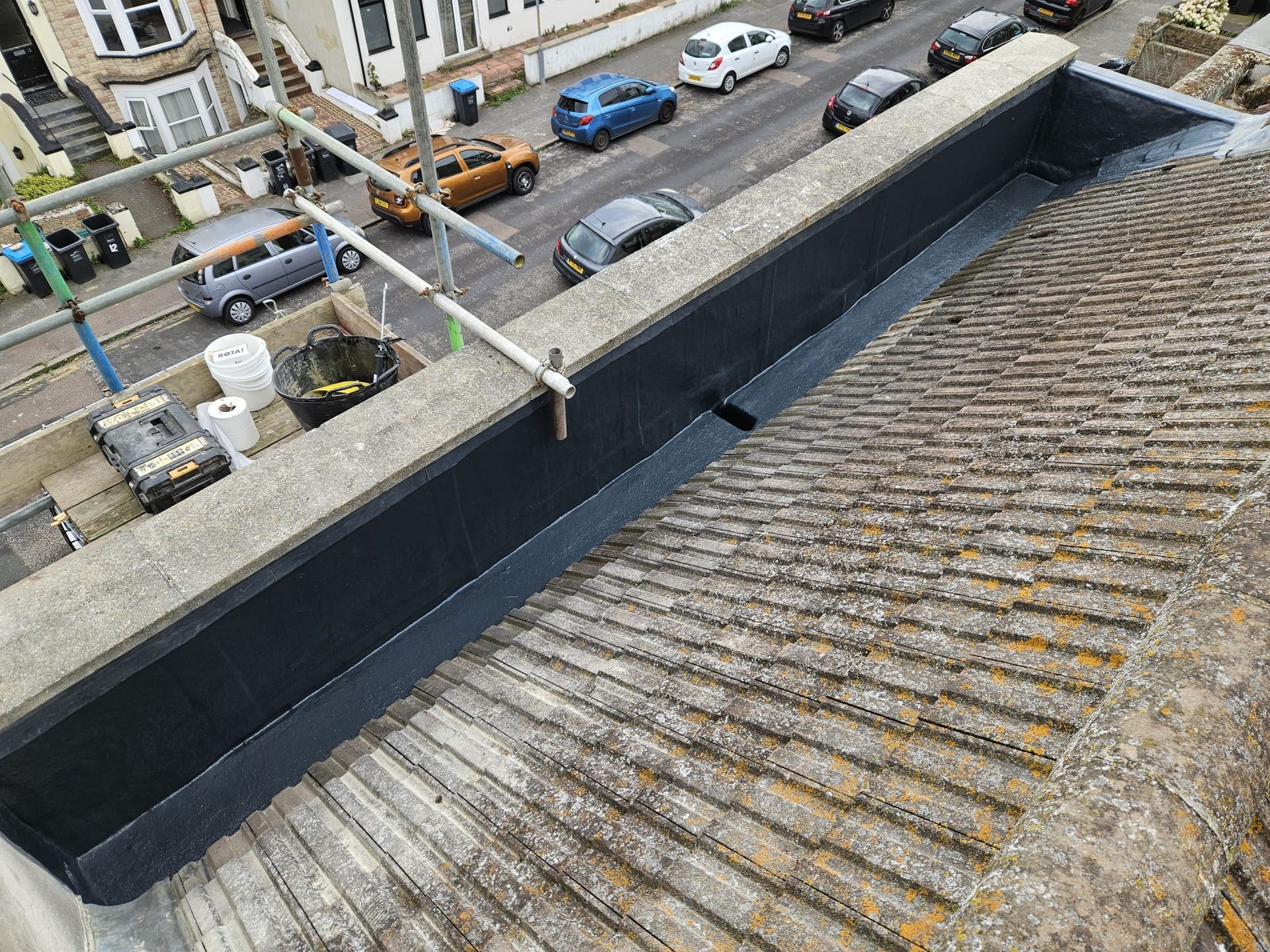 An aerial view of a roof with cars parked on the side of the road.