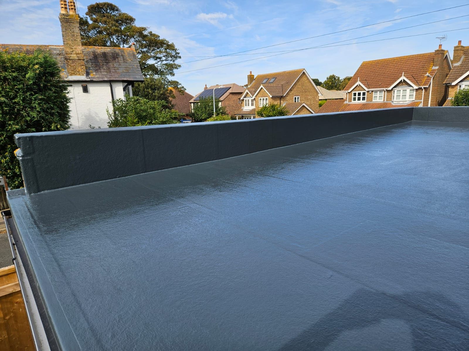 A black roof with a view of houses in the background.