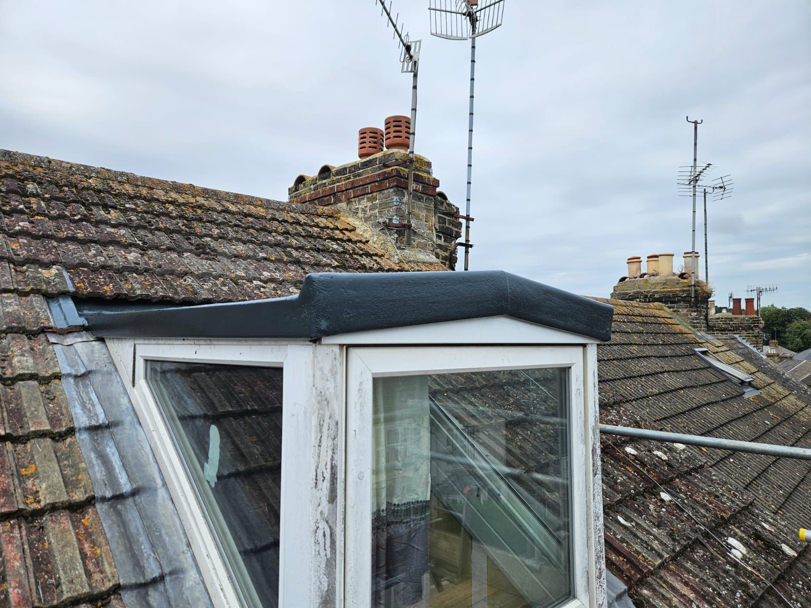 A roof with a window and a chimney on it.