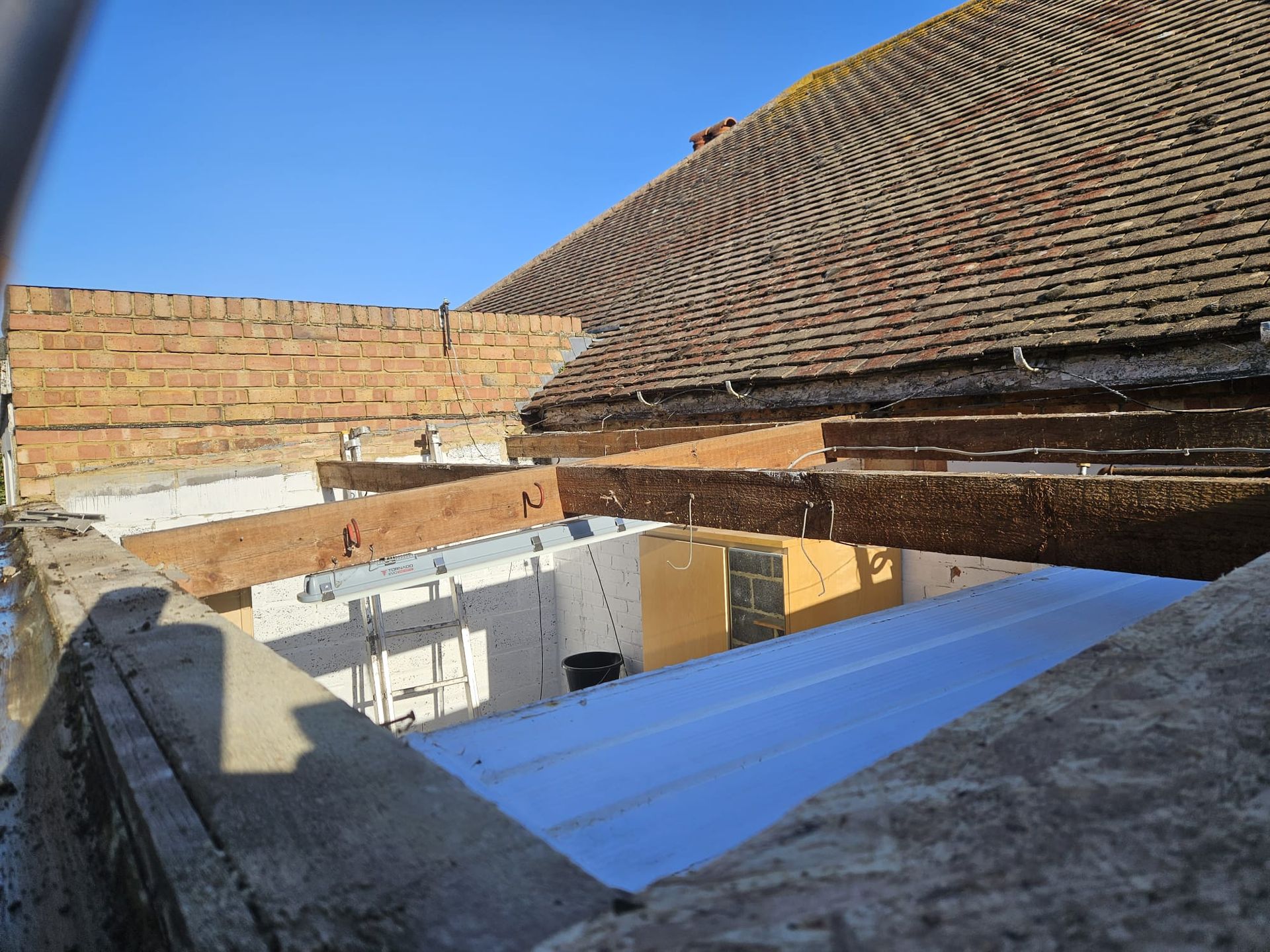 The roof of a building is being remodeled and a brick wall is being removed.