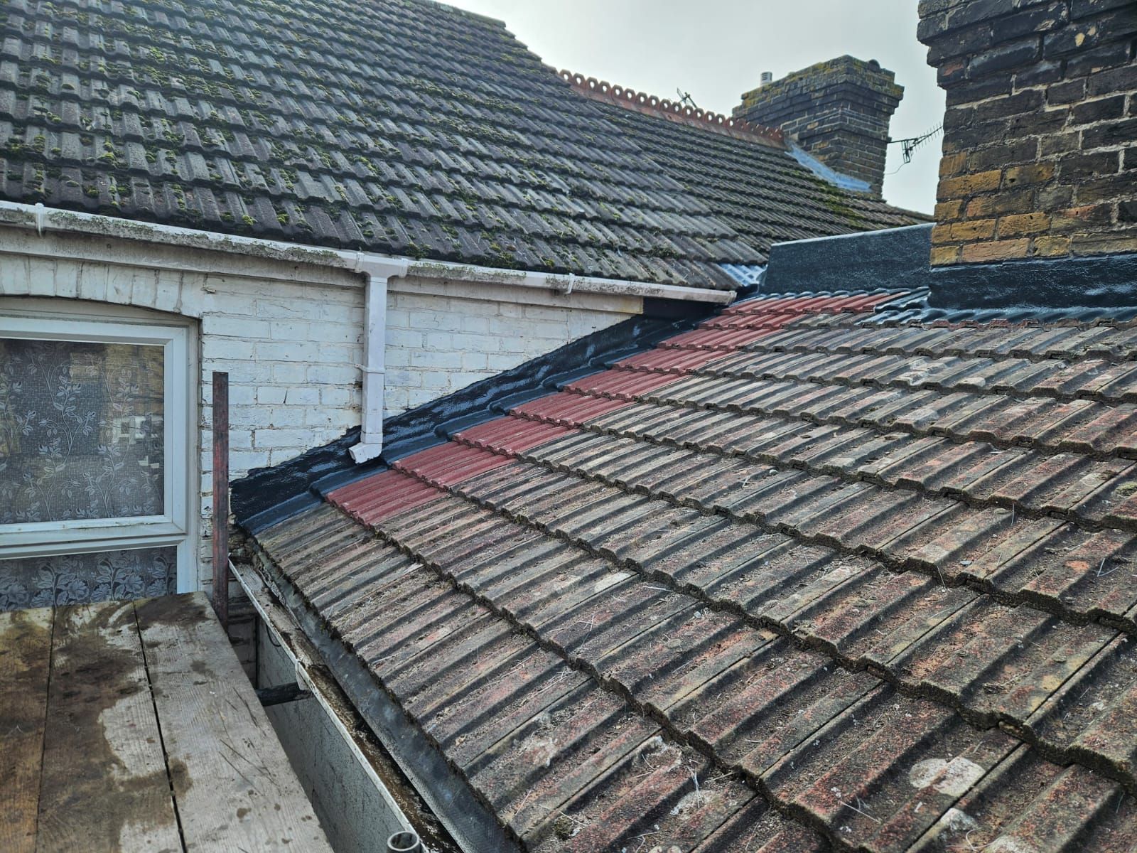 The roof of a house with a gutter and a chimney.