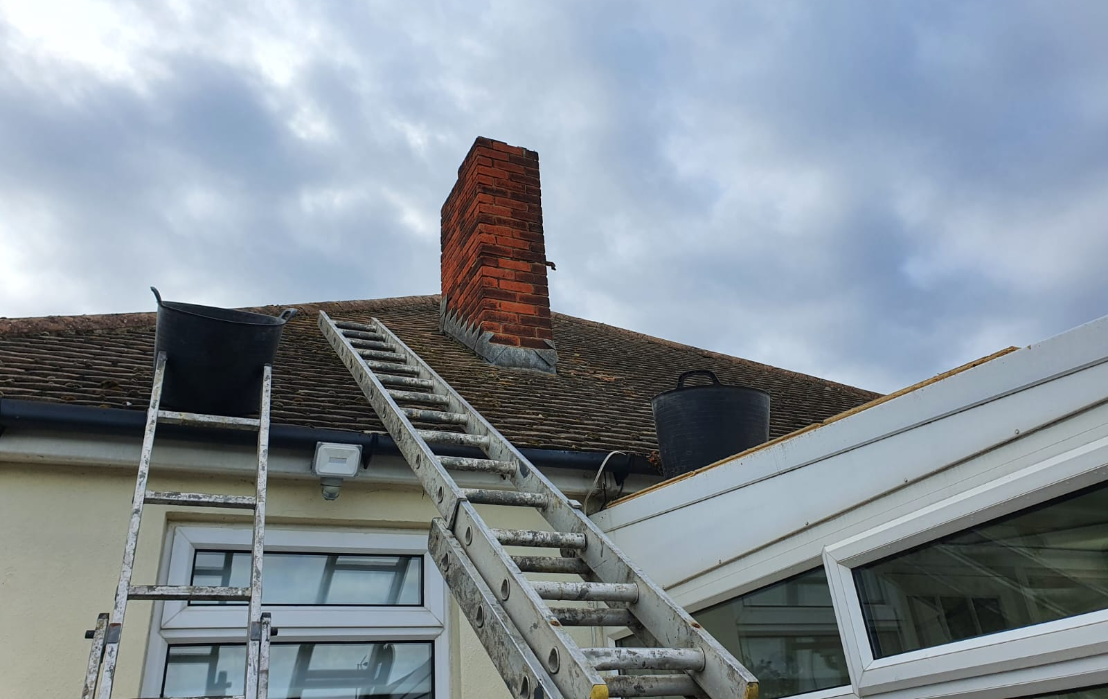 a ladder is sitting on the roof of a house next to a chimney .