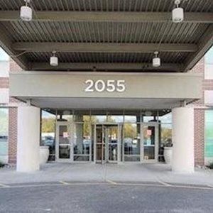 Entrance to building with address 2055, featuring columns, canopy, and glass doors.