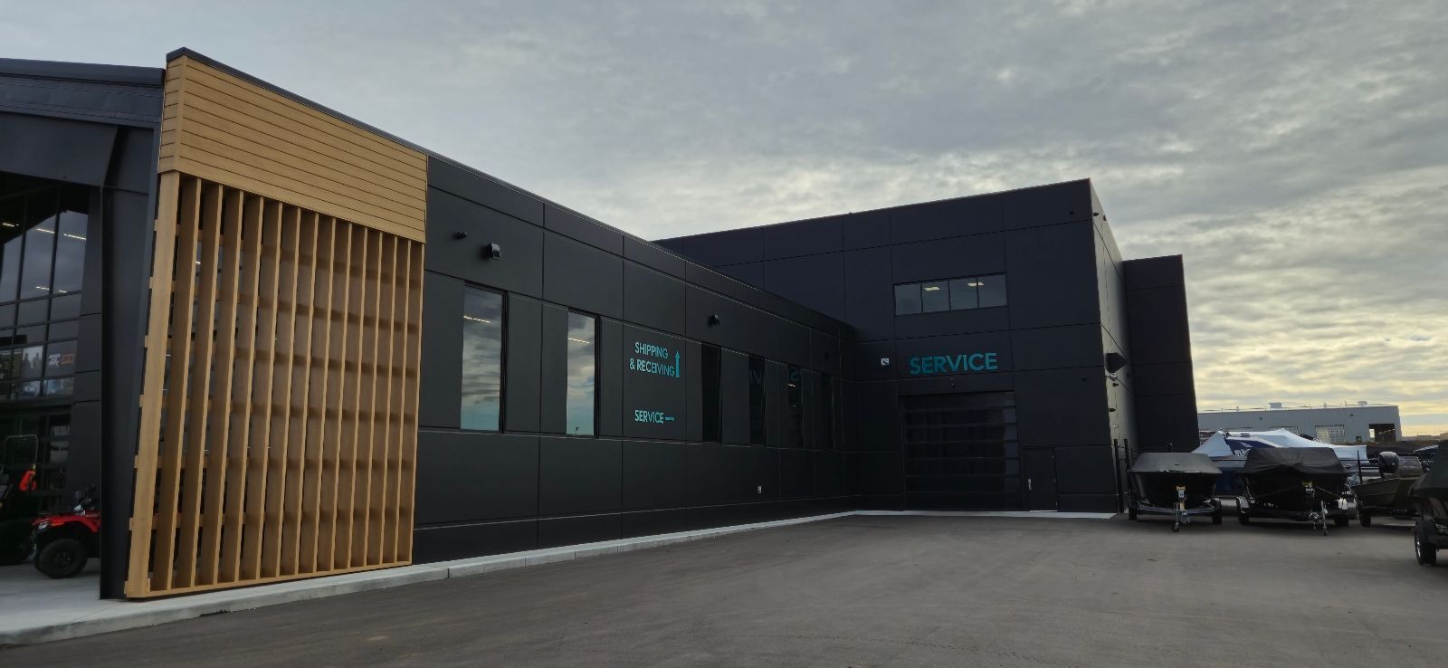 Exterior of a modern black building with wooden accents. The building has large windows and is parked.