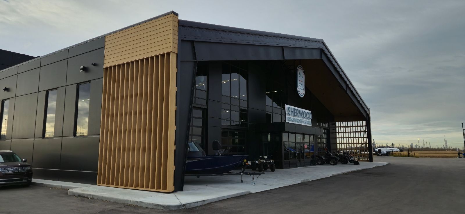 A modern building with dark cladding, wood accents, and large windows. Motorcycles are parked in front.