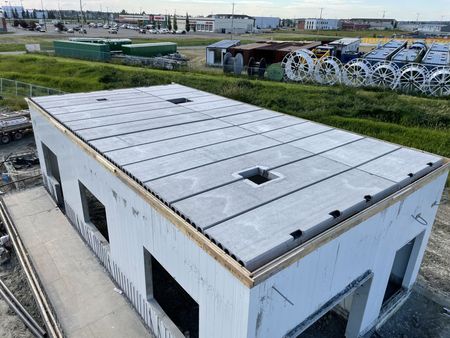 Partially constructed building with precast concrete panels for walls and roof, on a construction site.
