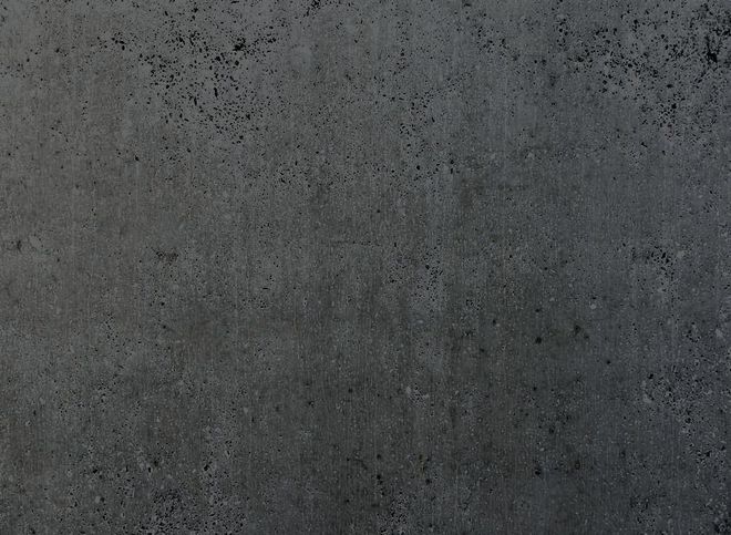 Dark gray, textured concrete surface with small dark spots.