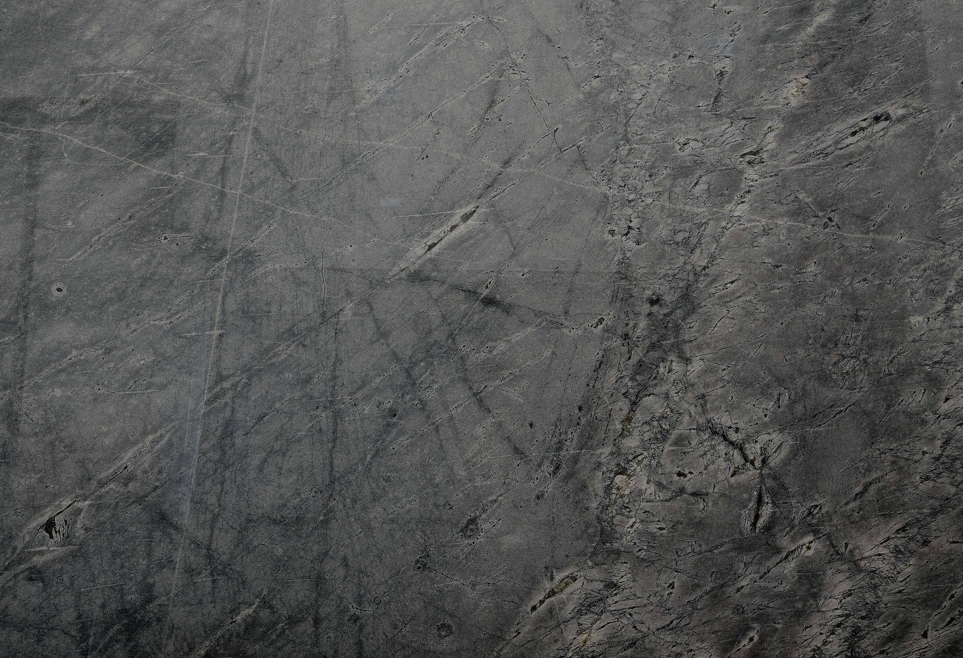 Dark gray, textured stone surface with subtle patterns and variations in tone.