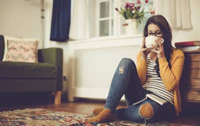 A girl drinking coffee on the floor of her cozy living room