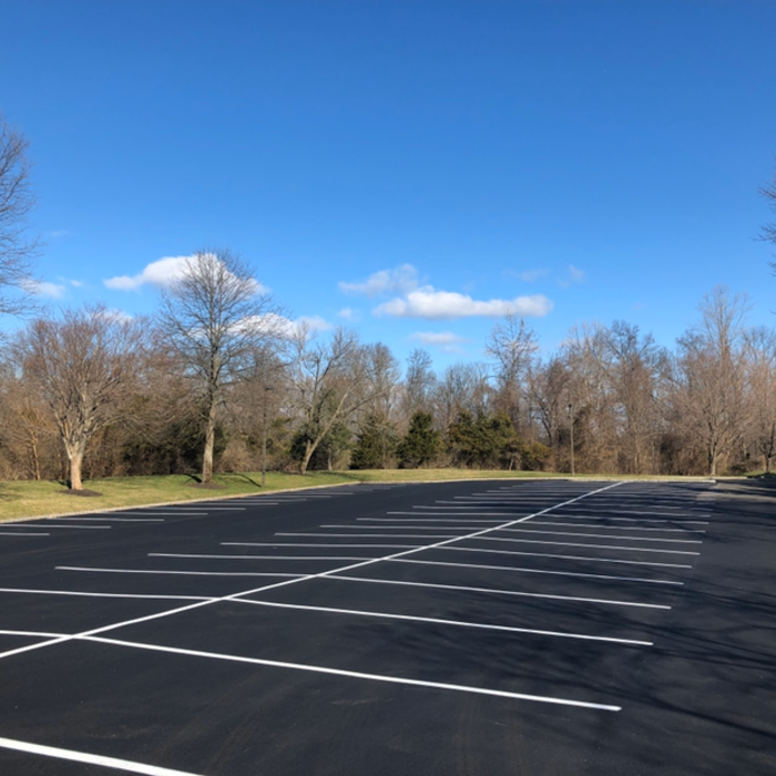 A construction worker is working on a parking lot.