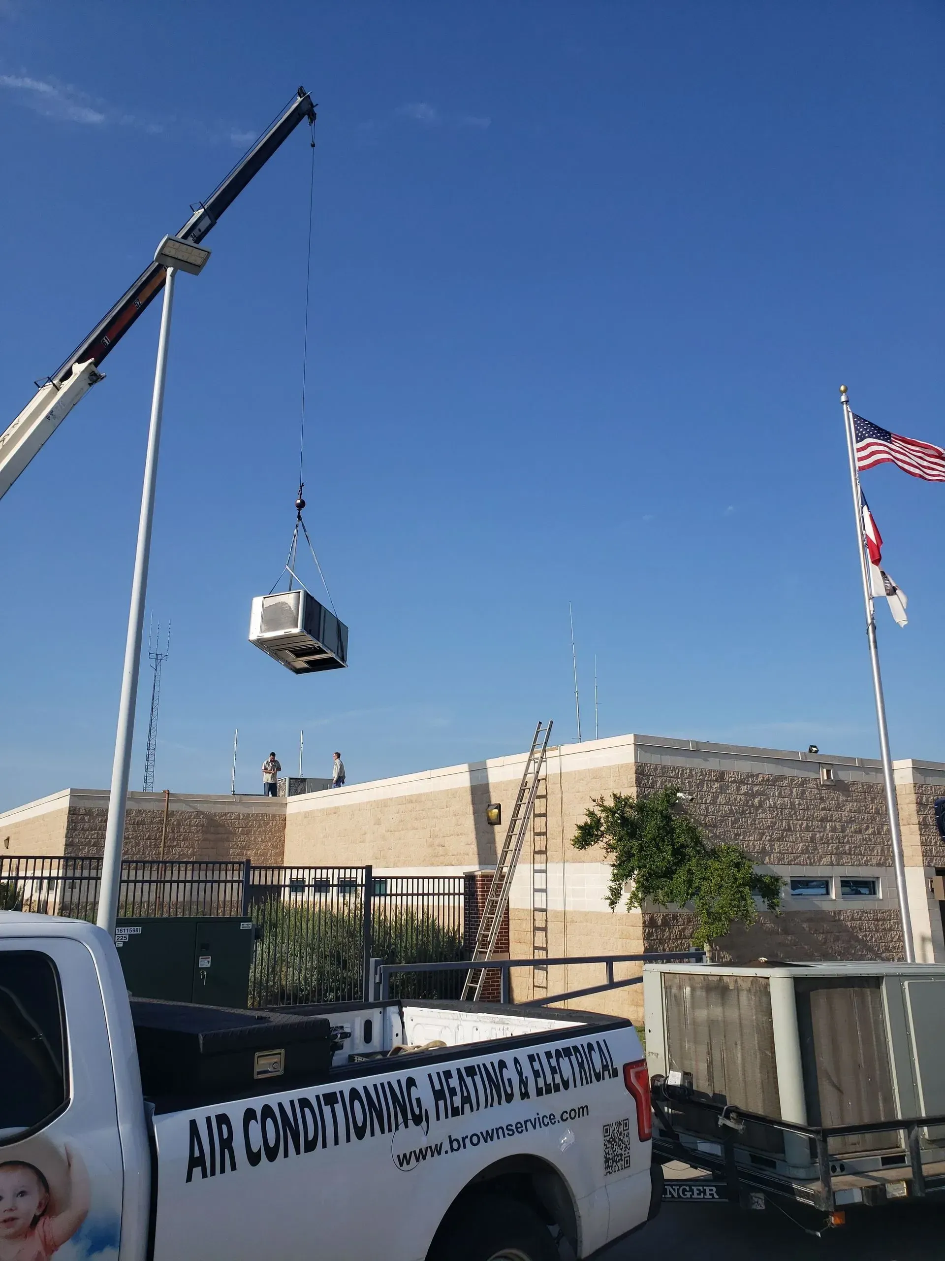 An air conditioning truck is being lifted by a crane