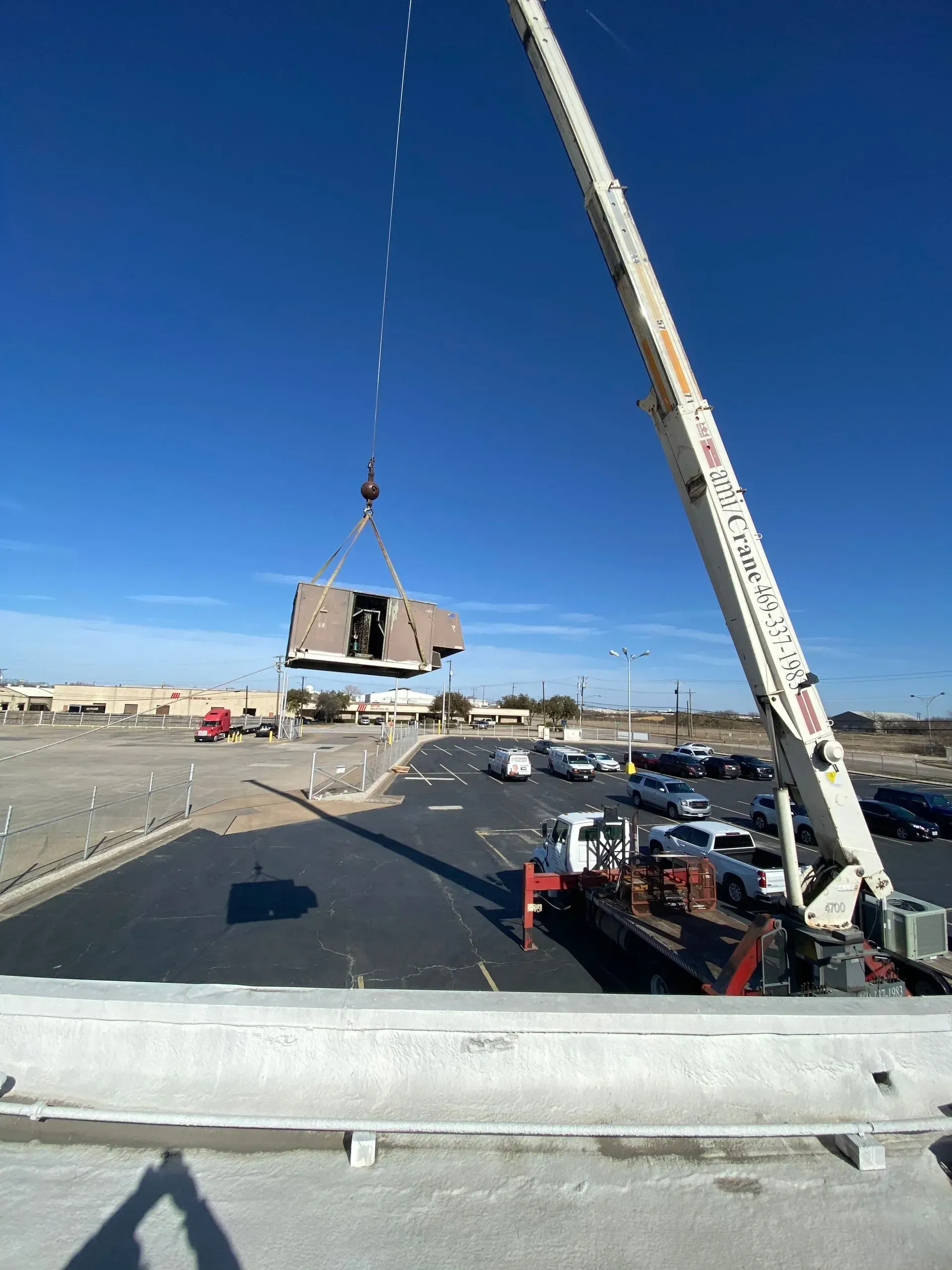 A large crane is lifting a building in a parking lot.