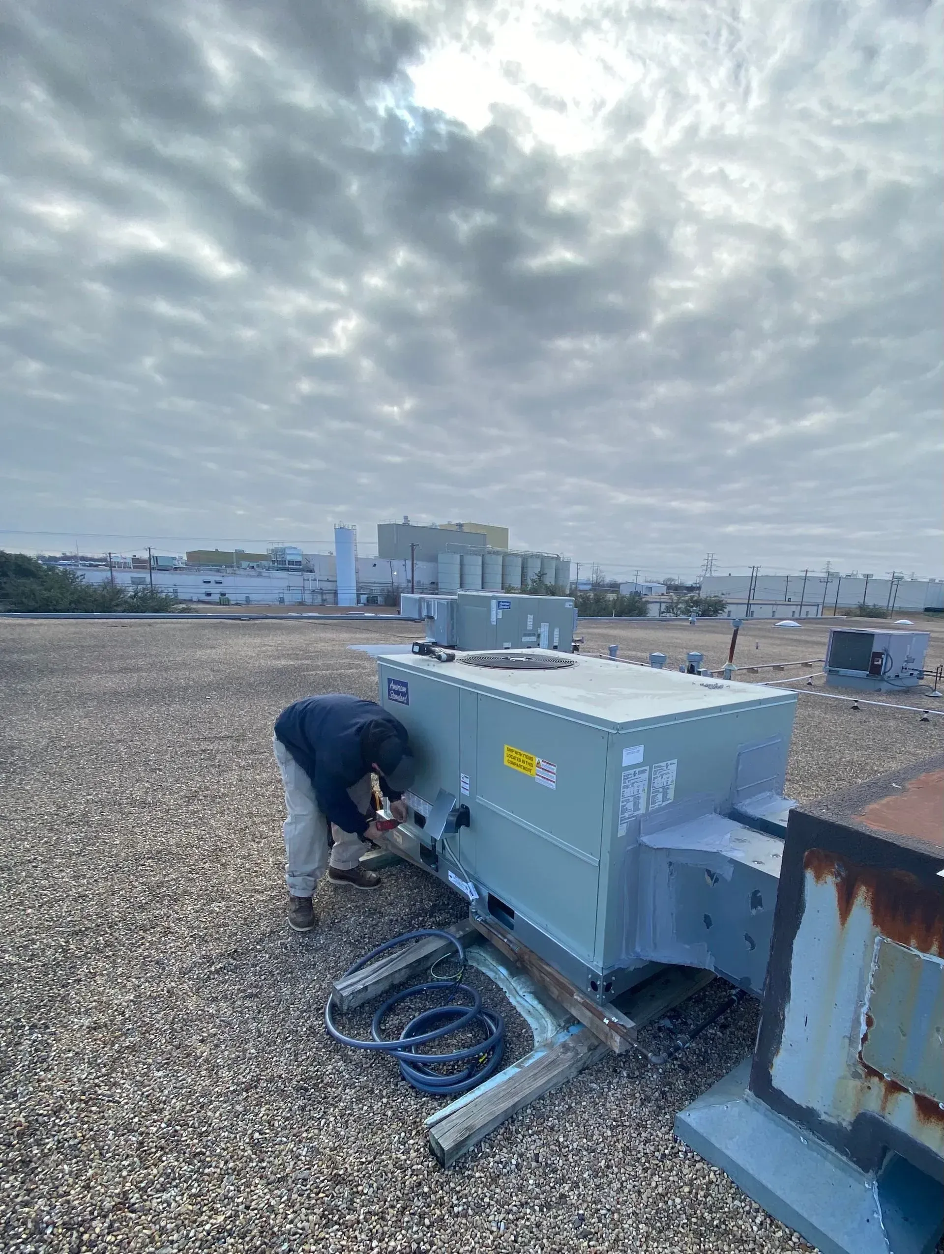 A man is working on a machine on the roof of a building.