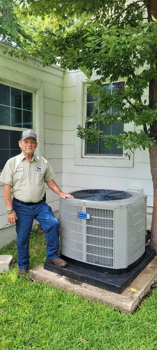 A man is standing next to an air conditioner in front of a house.