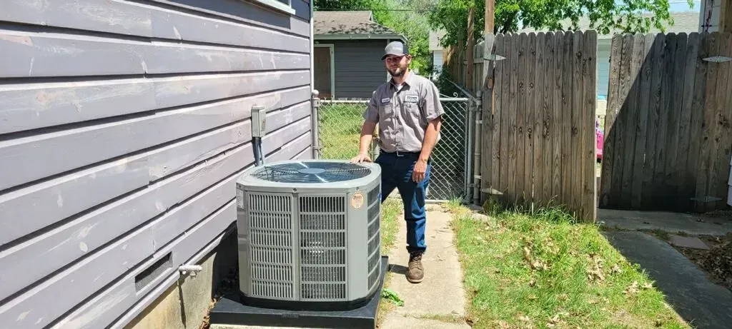 A man is standing next to an air conditioner outside of a house.