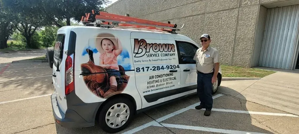 A man is standing next to a white van with a picture of a baby on the side.